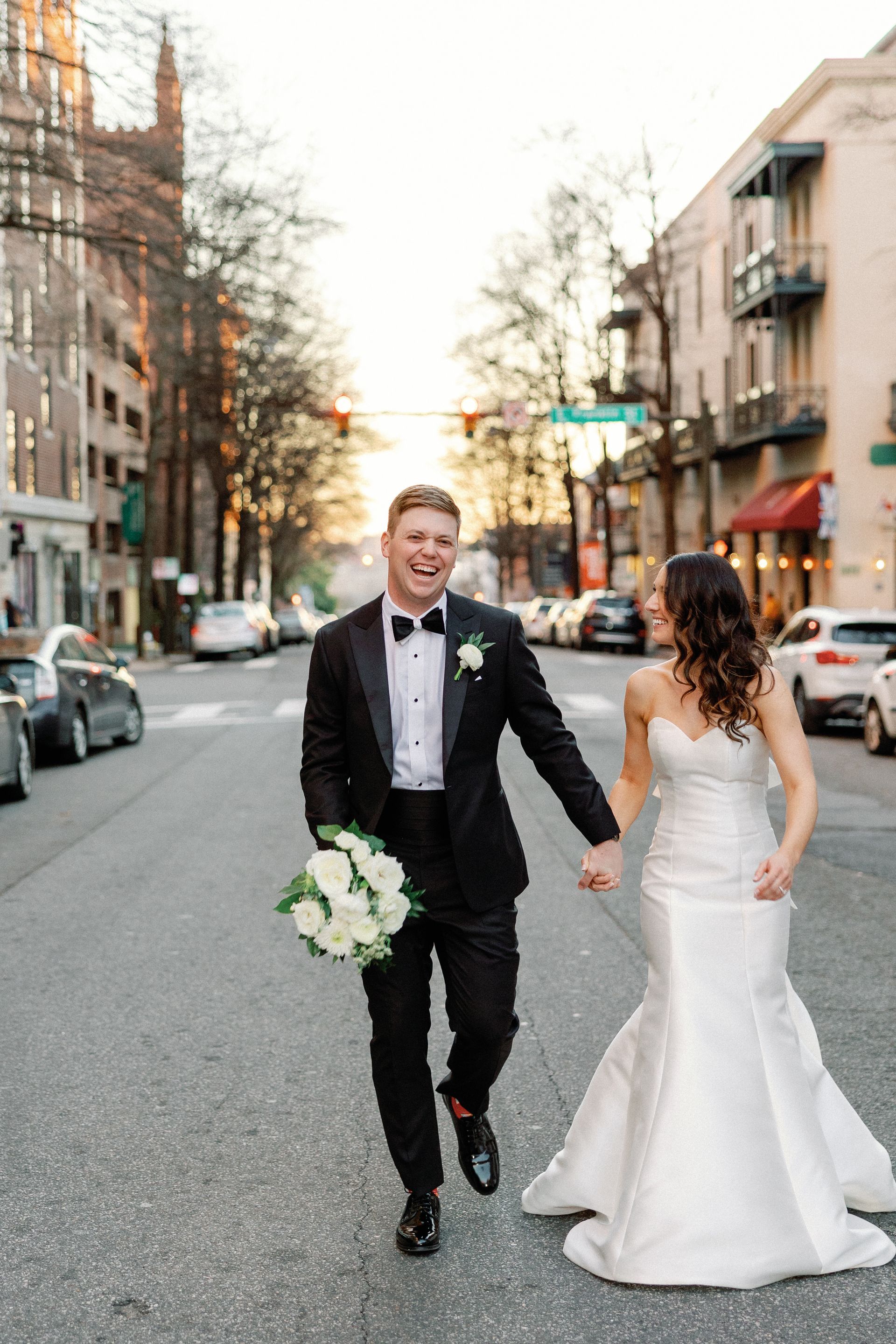 A bride and groom are walking down the street holding hands.