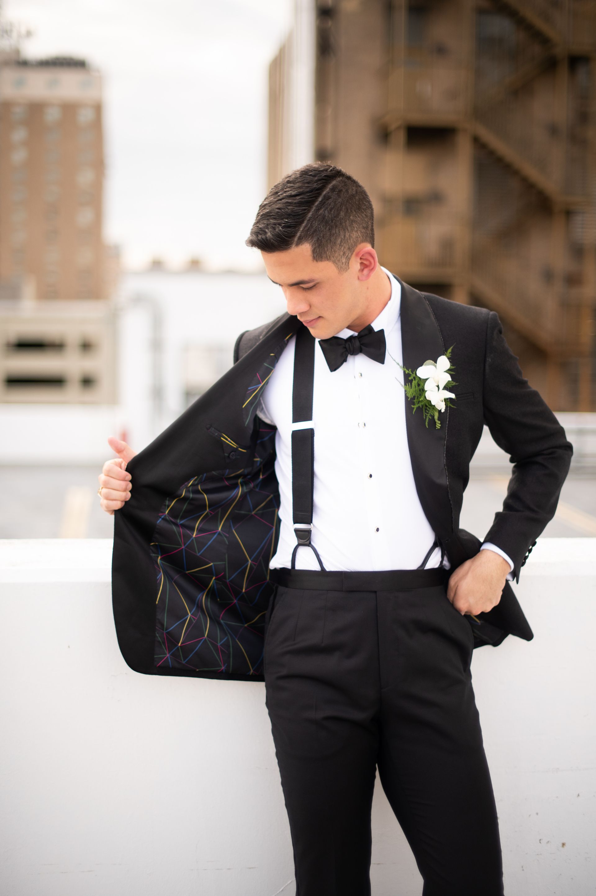 A man in a tuxedo and bow tie is standing on a balcony.