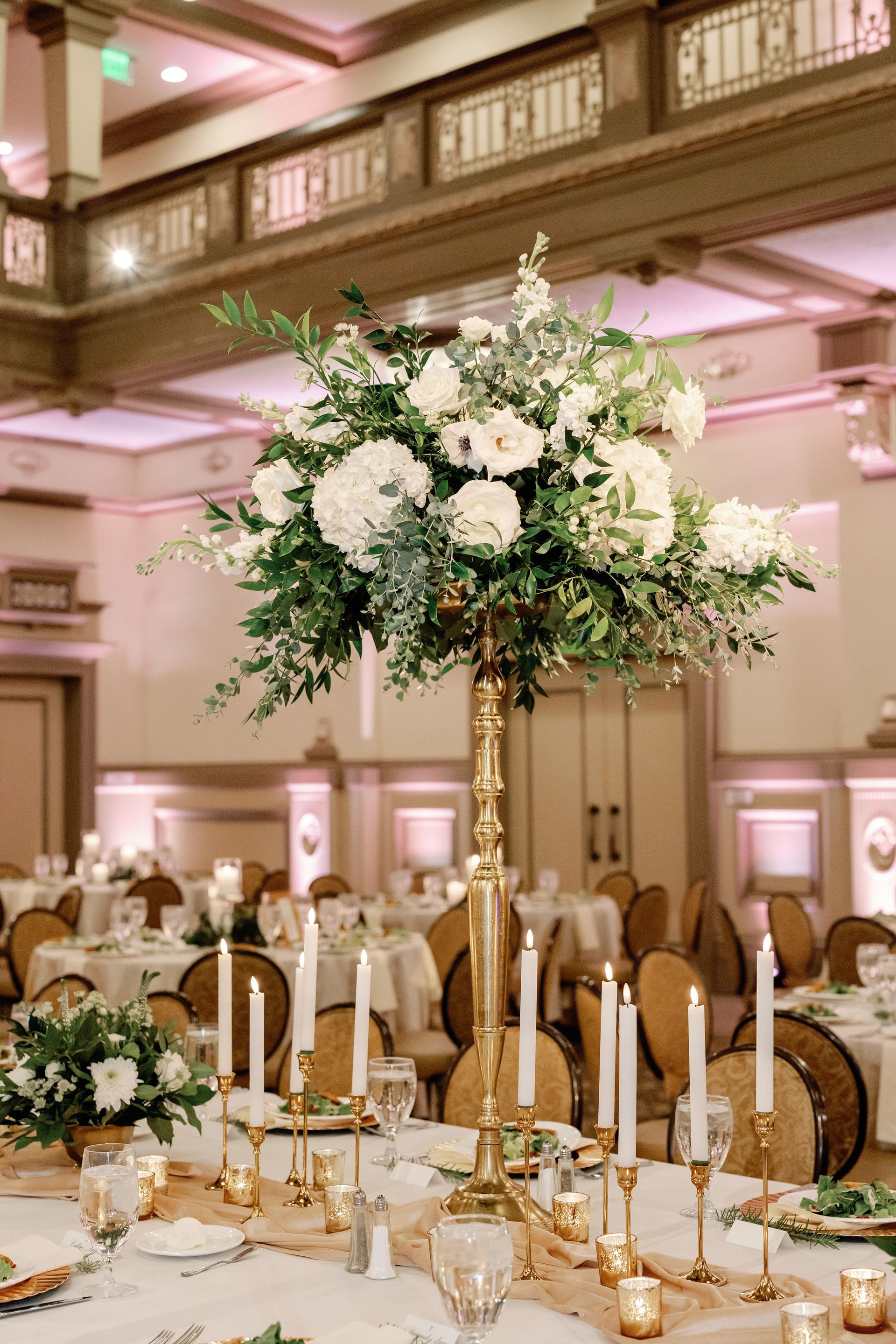 A table set for a wedding reception with candles and flowers on it.