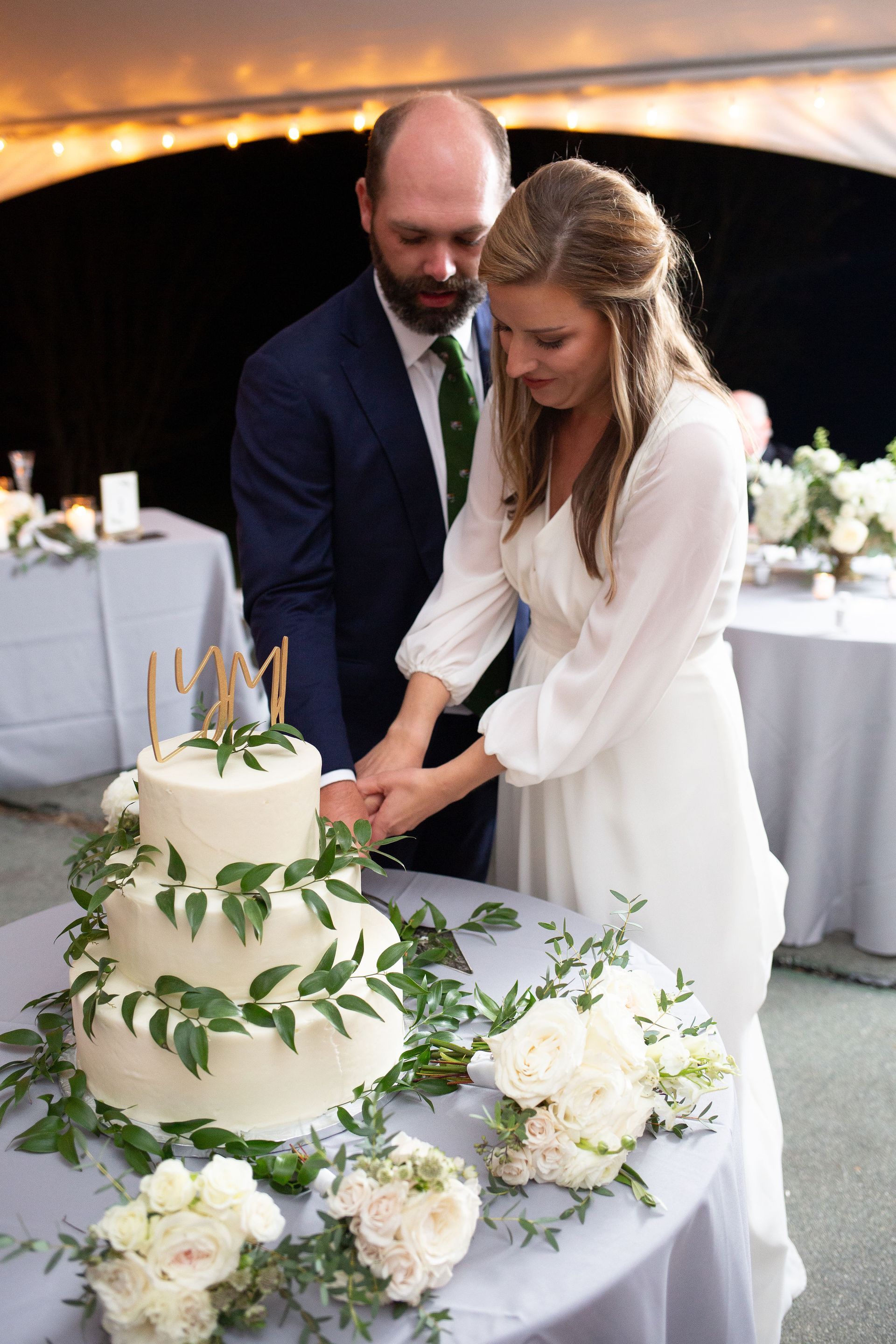 A bride and groom are cutting their wedding cake on a table.