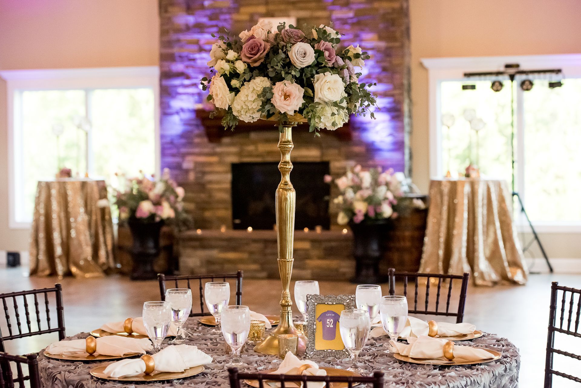 A table with a vase of flowers on it in front of a fireplace.