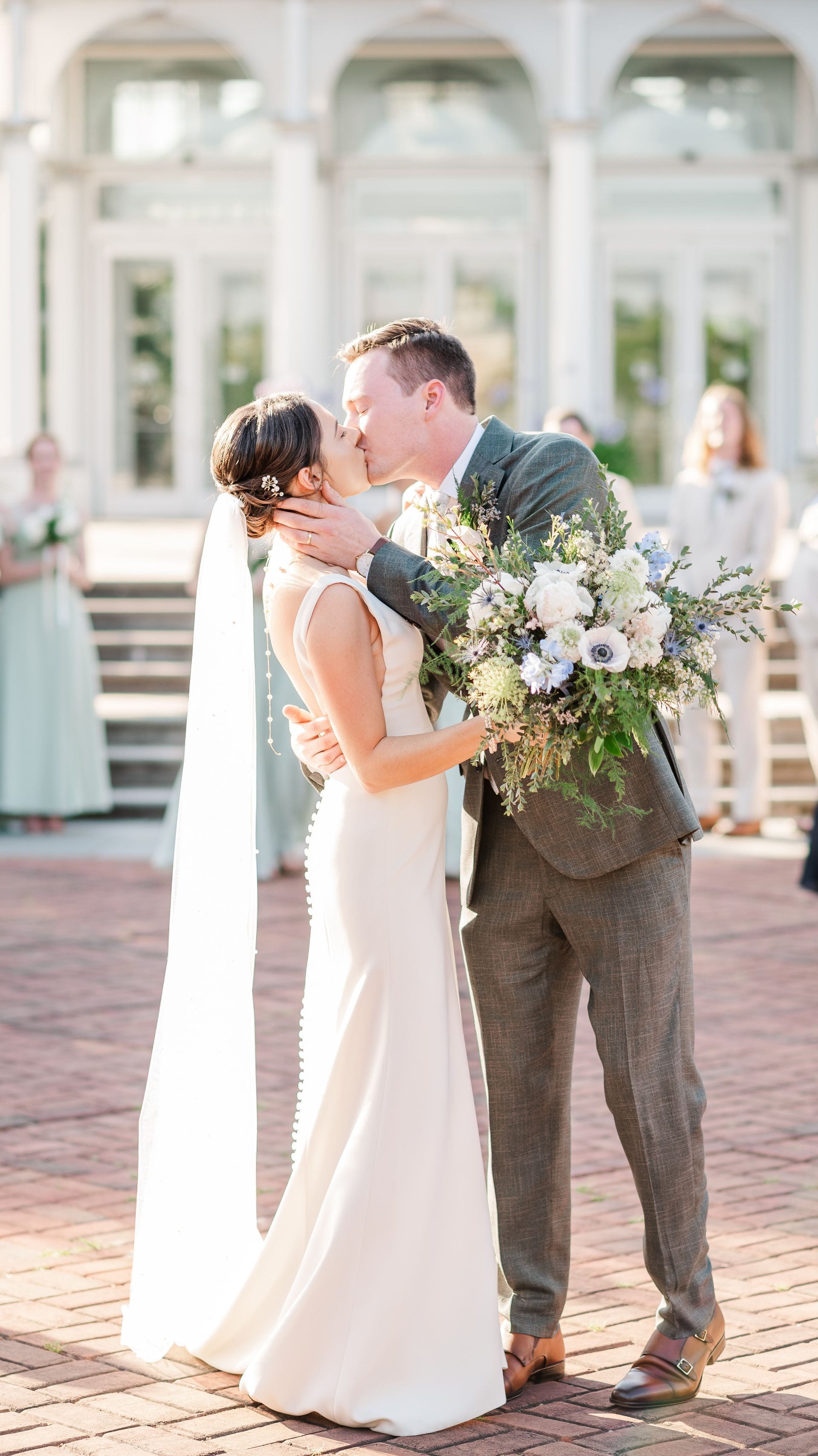 A bride and groom are kissing in front of a building.