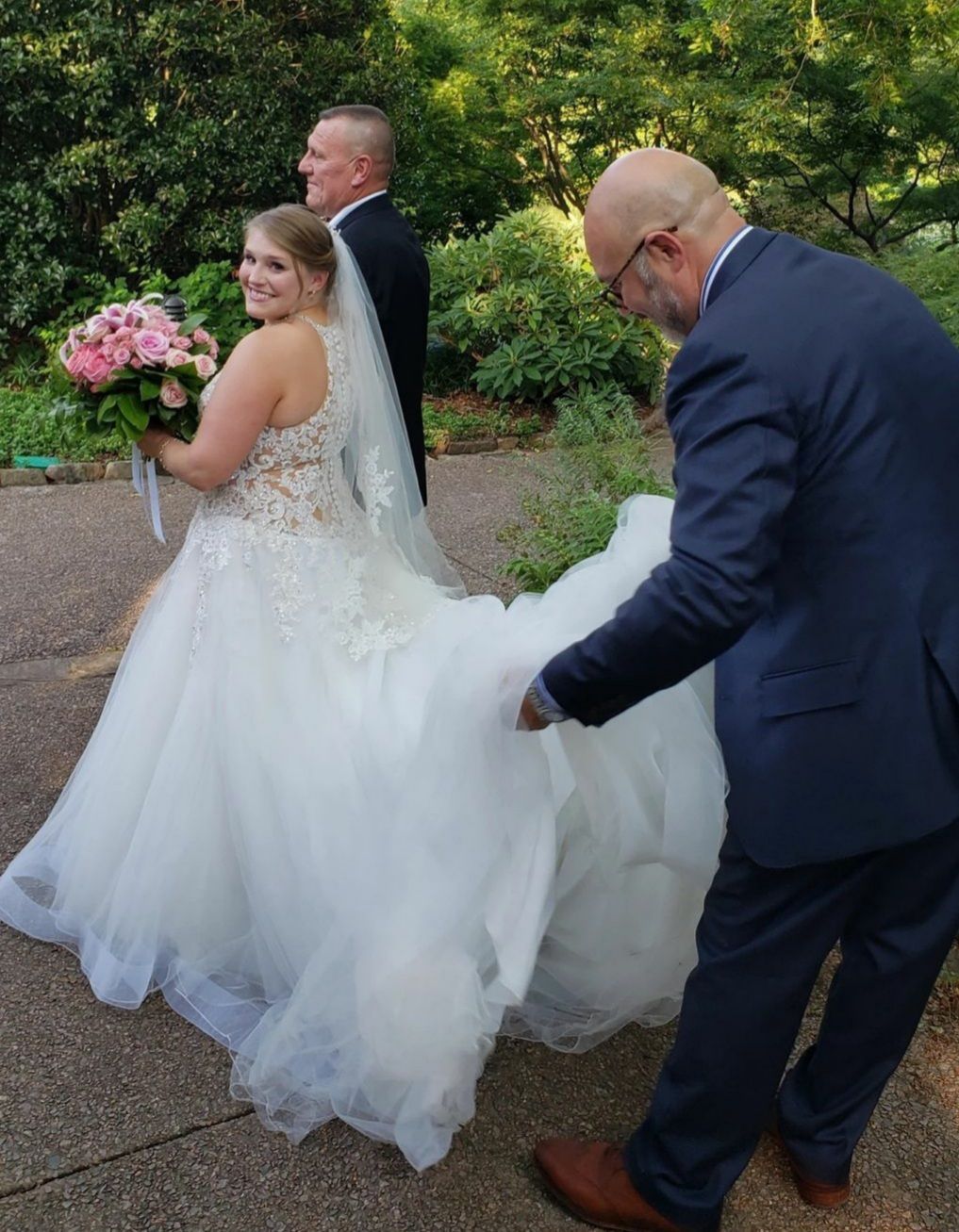 A bride in a wedding dress is being helped by a man in a suit.