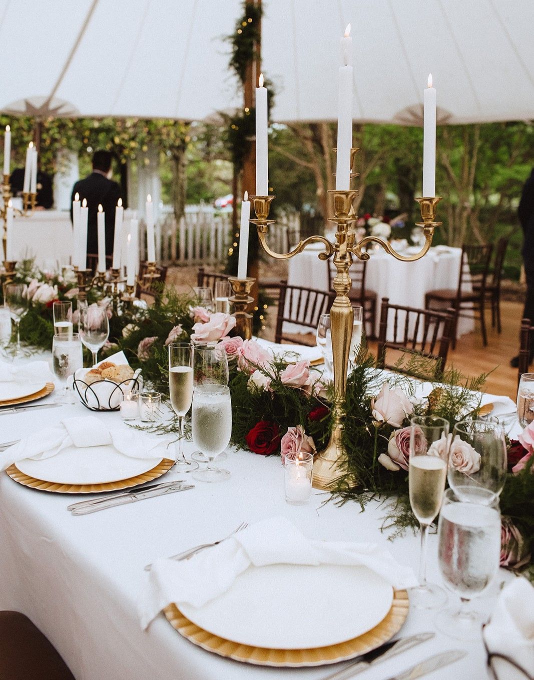 A long table with plates , candles , wine glasses and flowers on it.
