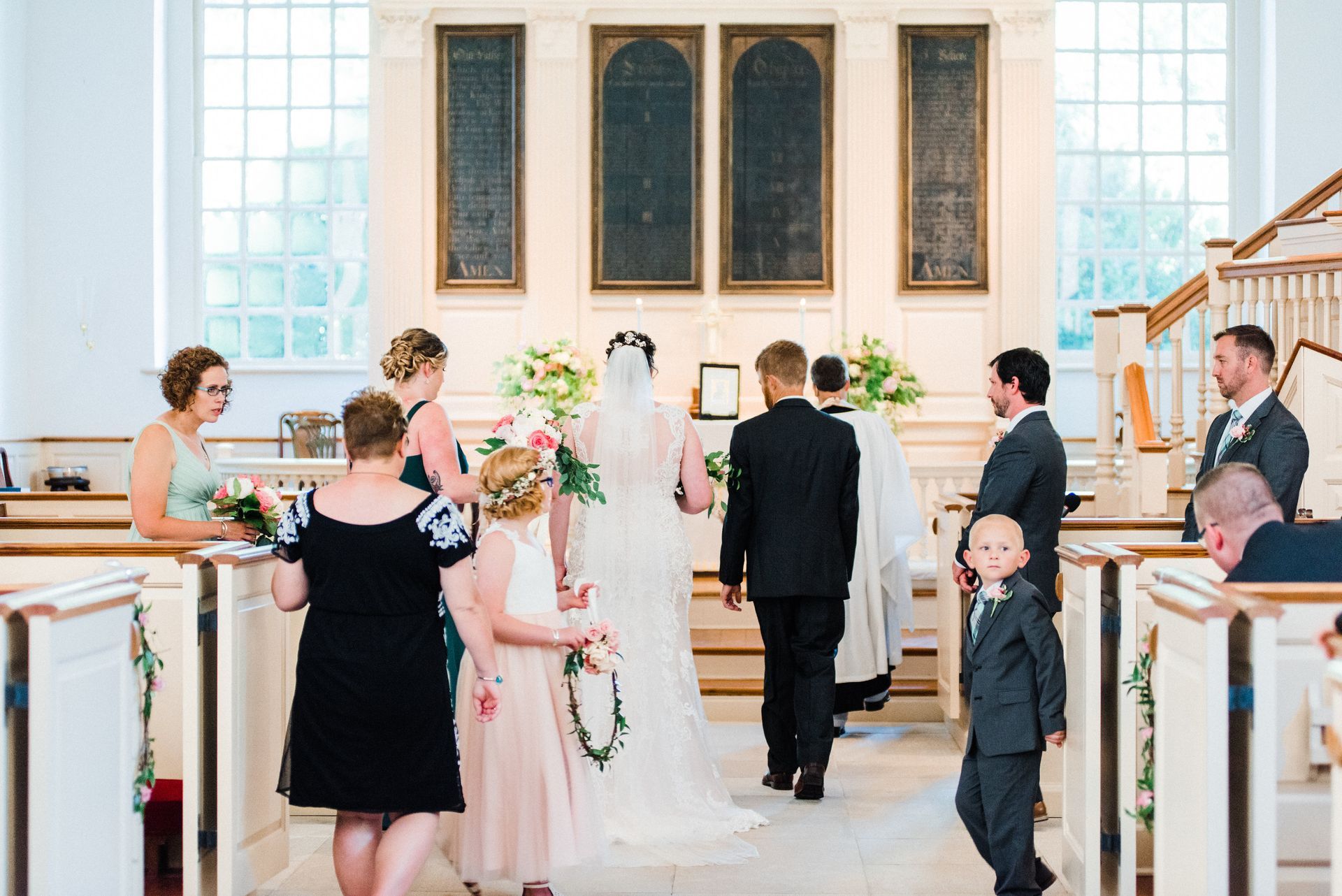 A bride and groom are walking down the aisle of a church with their wedding party.