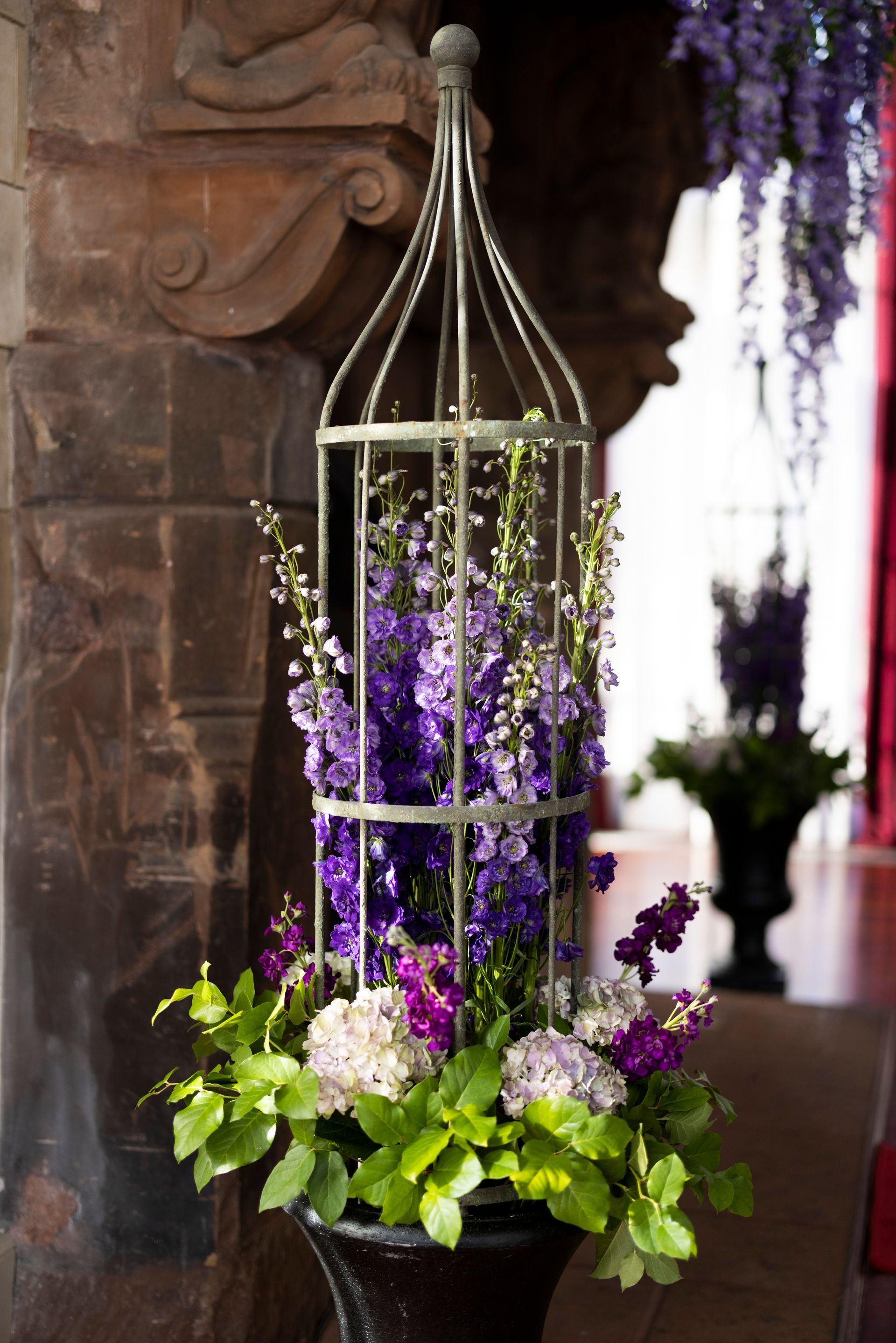A bird cage filled with purple and white flowers