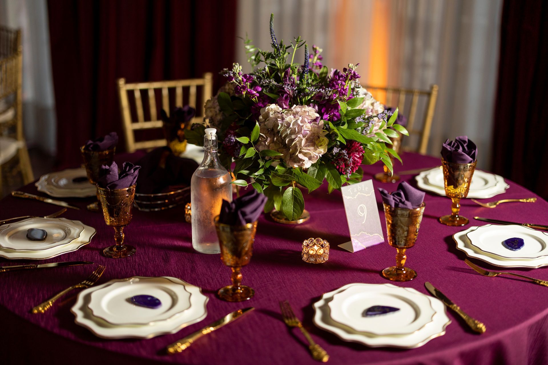 A table set for a wedding reception with plates , utensils , and a vase of flowers.