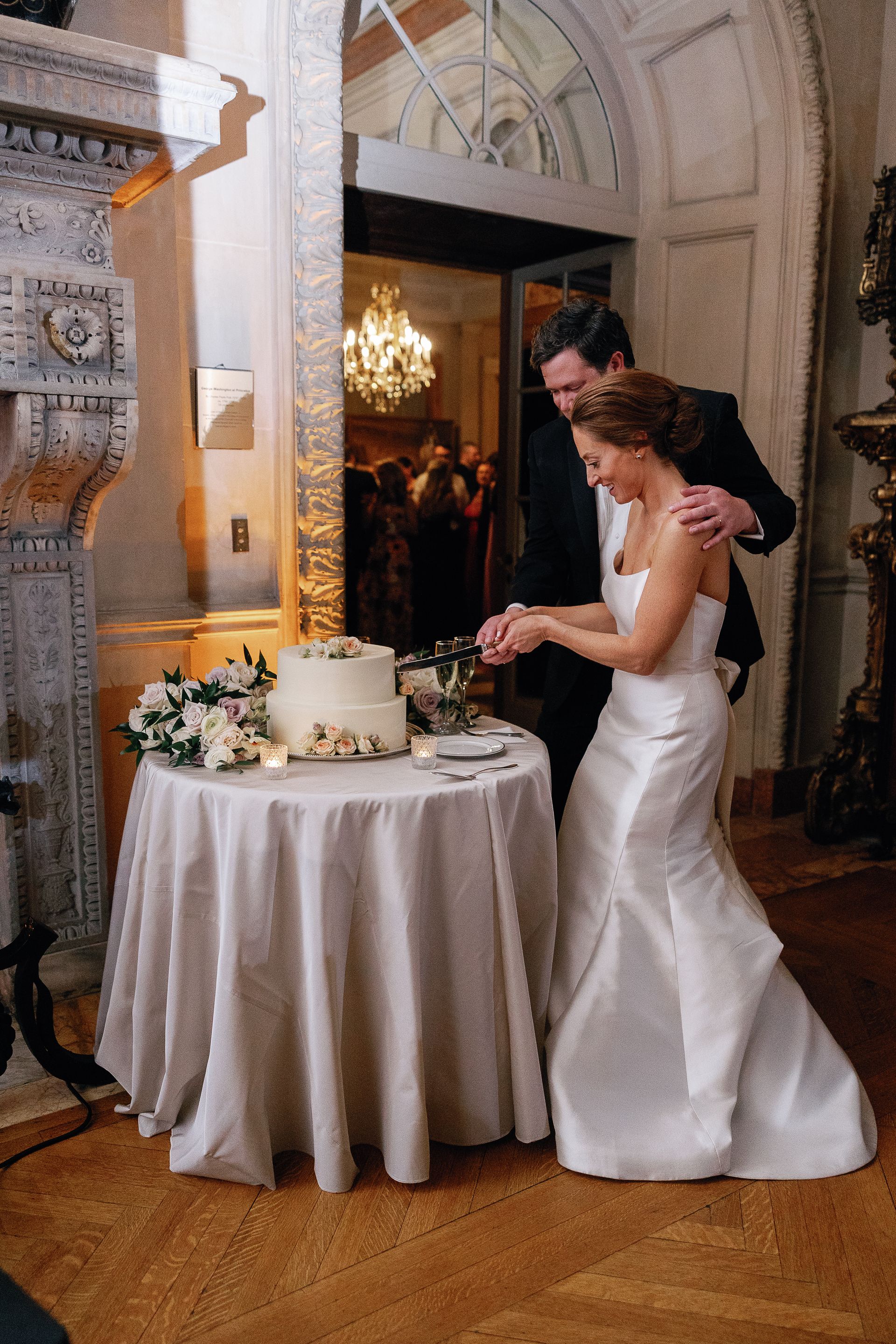 A bride and groom are cutting their wedding cake on a table.