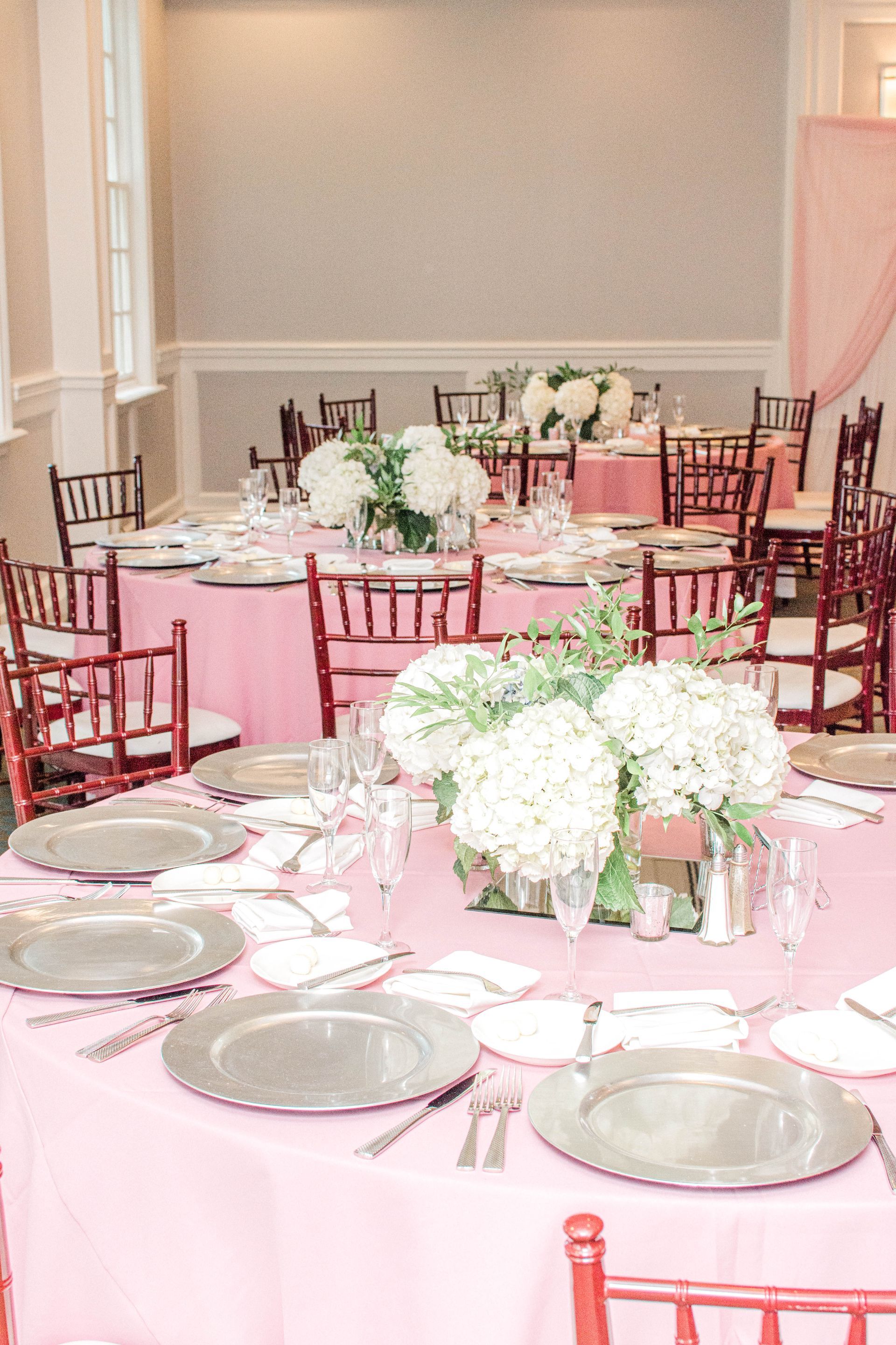 A room filled with tables and chairs set up for a wedding reception.