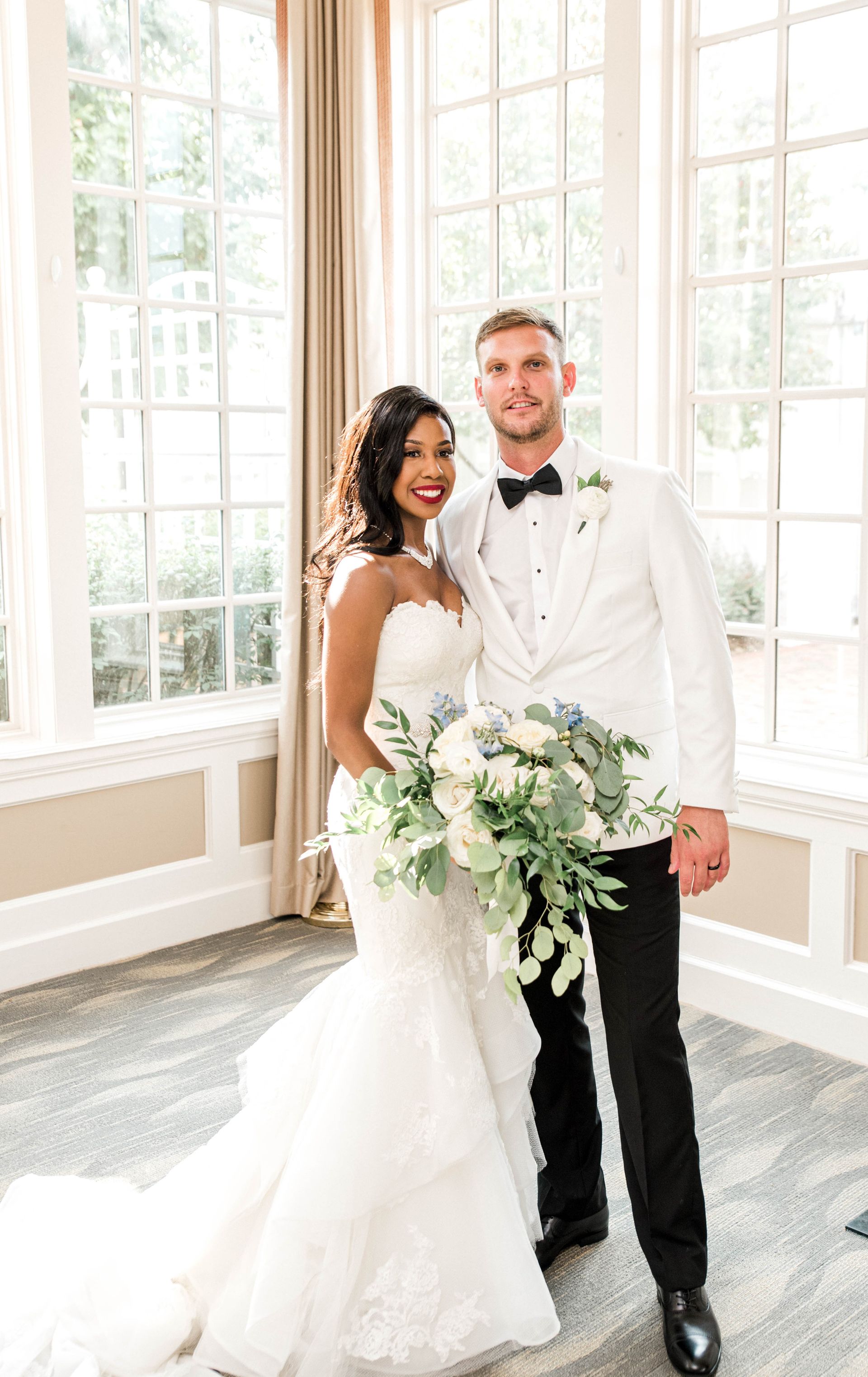 A bride and groom are posing for a picture in front of a window.