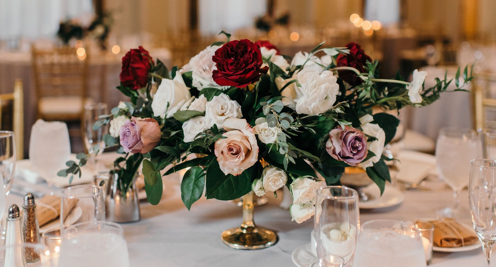 A table set for a wedding reception with a vase of flowers on it.