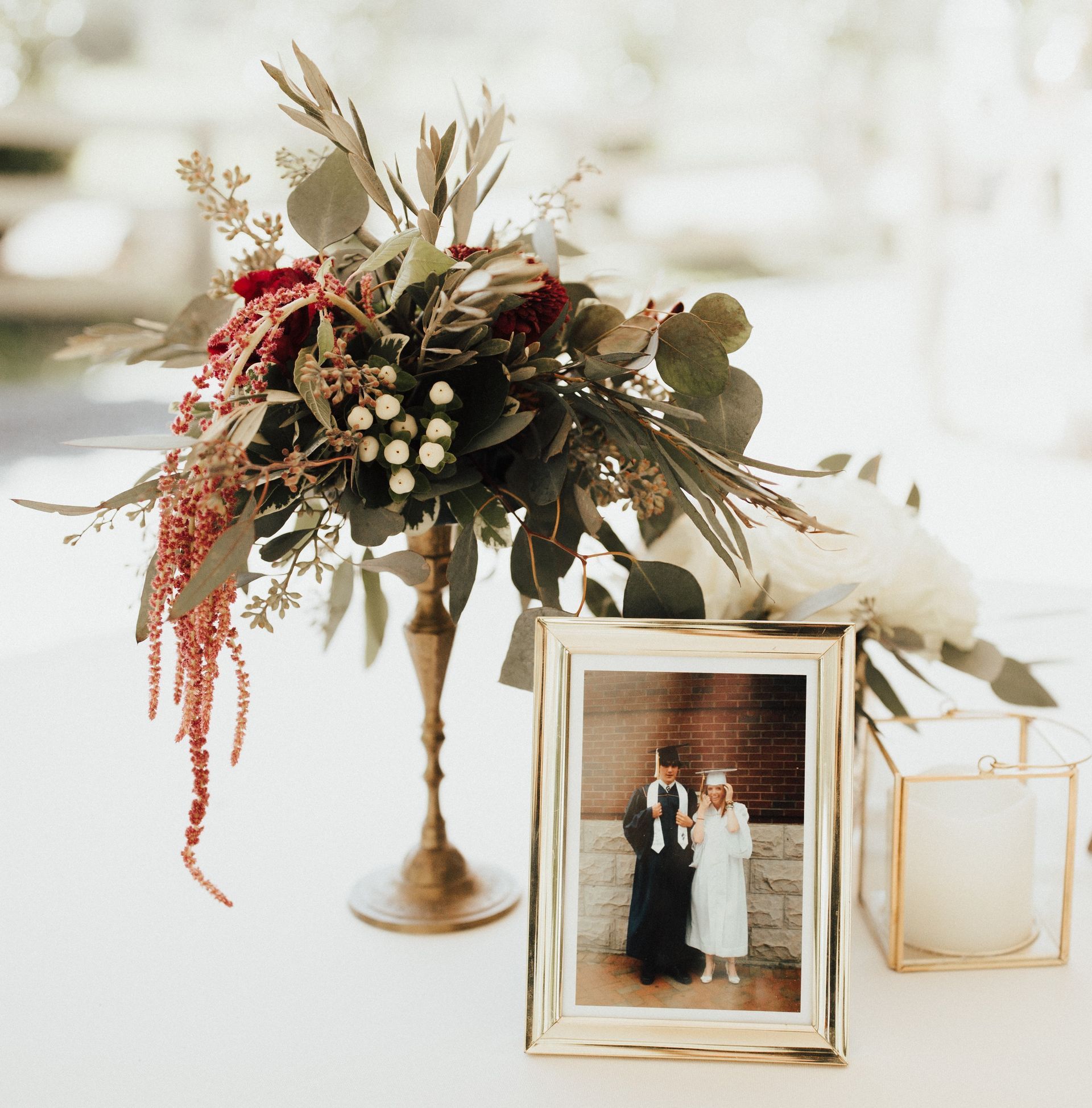 A framed picture of a bride and groom sits on a table next to a vase of flowers
