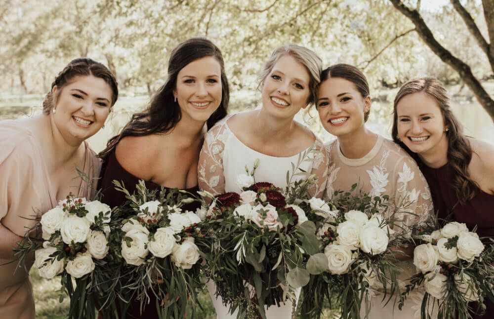 A bride and her bridesmaids are posing for a picture with their bouquets of flowers.
