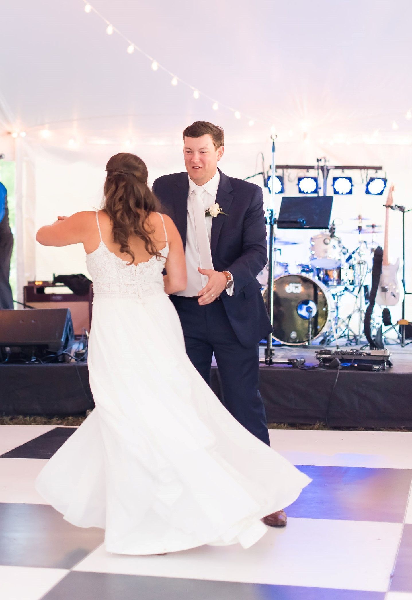 A bride and groom are dancing on a checkered dance floor.