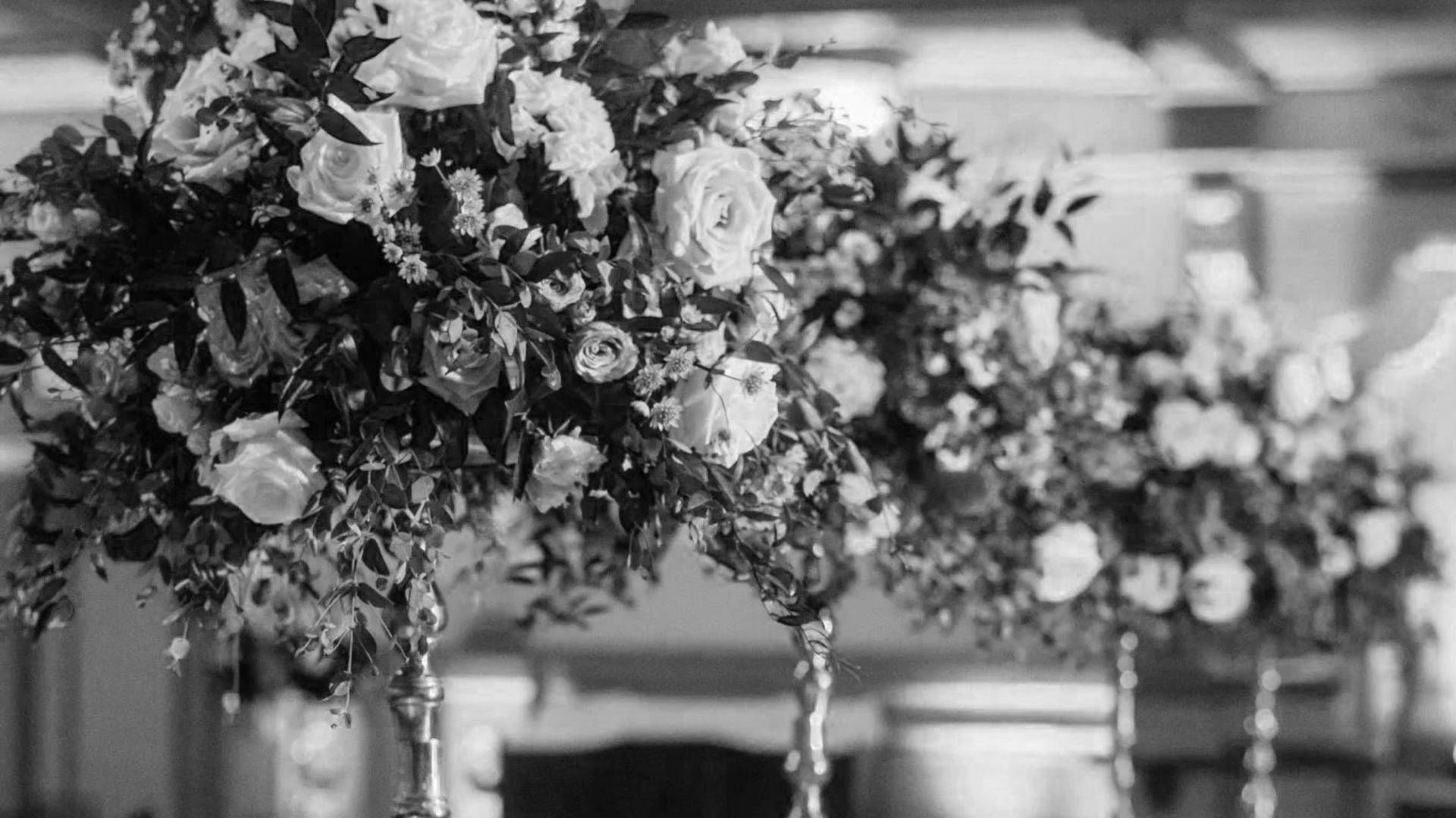 A black and white photo of a row of vases filled with flowers.