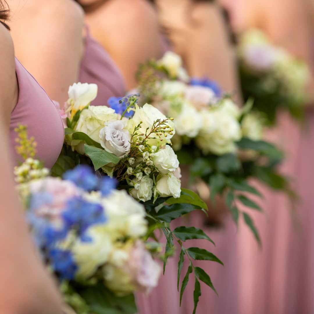 A group of bridesmaids in pink dresses holding bouquets of flowers.