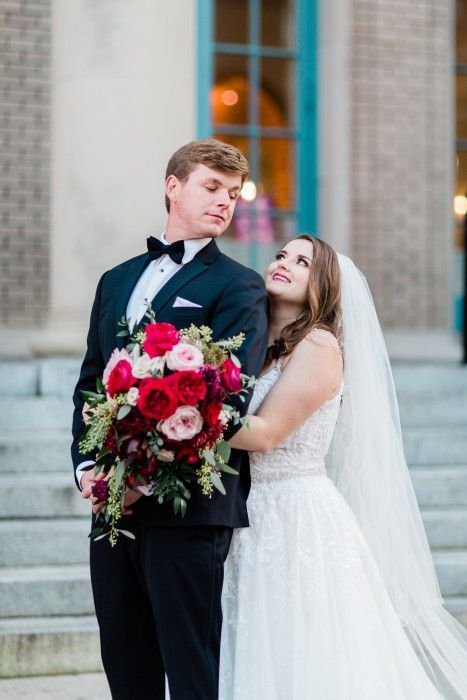 A bride and groom are posing for a picture in front of a building.