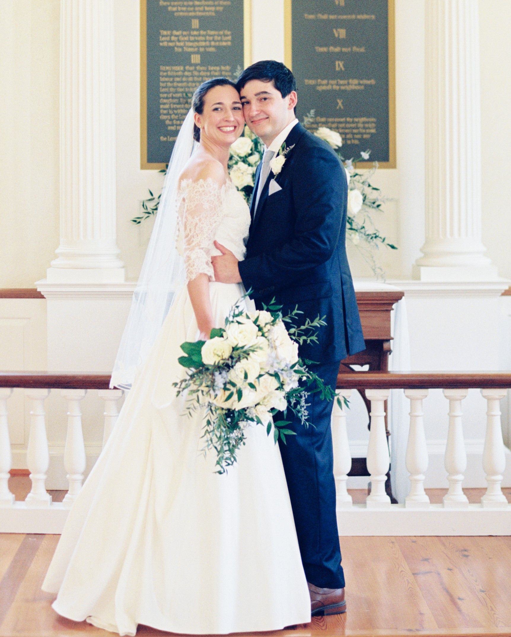 A bride and groom pose for a picture in a church