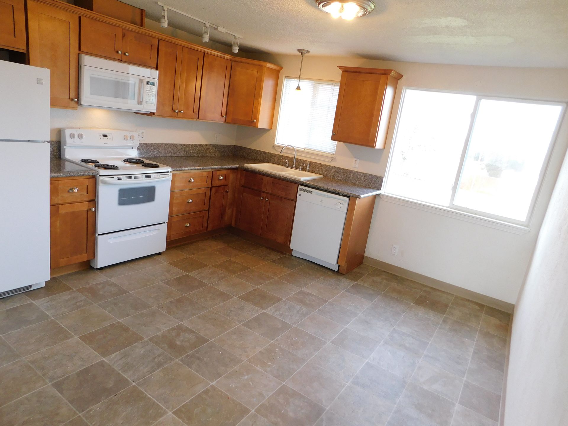 Kitchen with light brown cabinets, white appliances, and tiled floor.