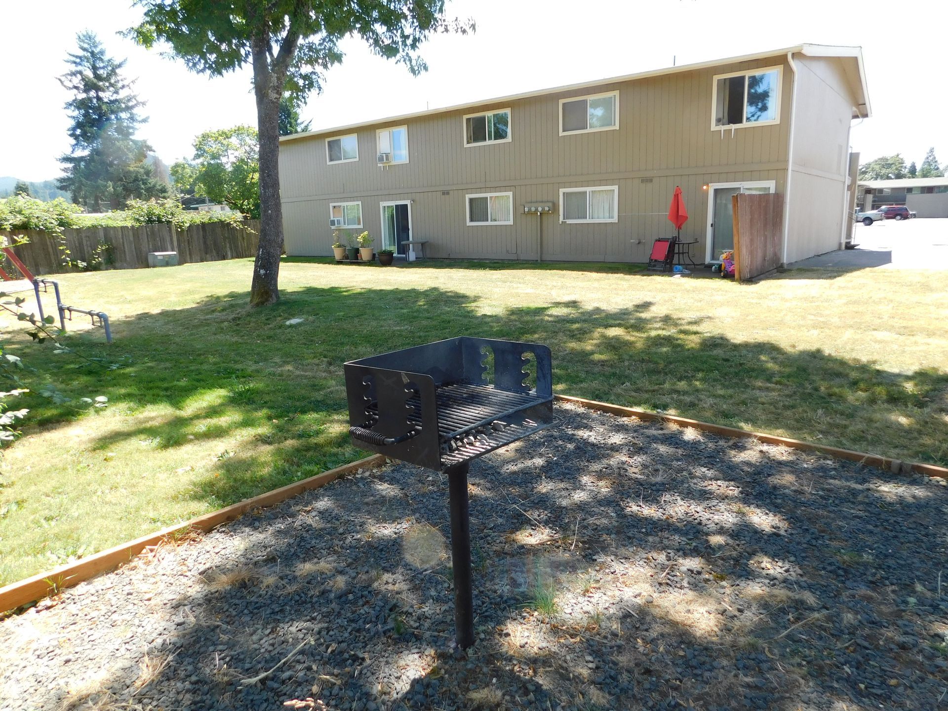 Apartment complex exterior with grass walkway, stairway, and blue sky.