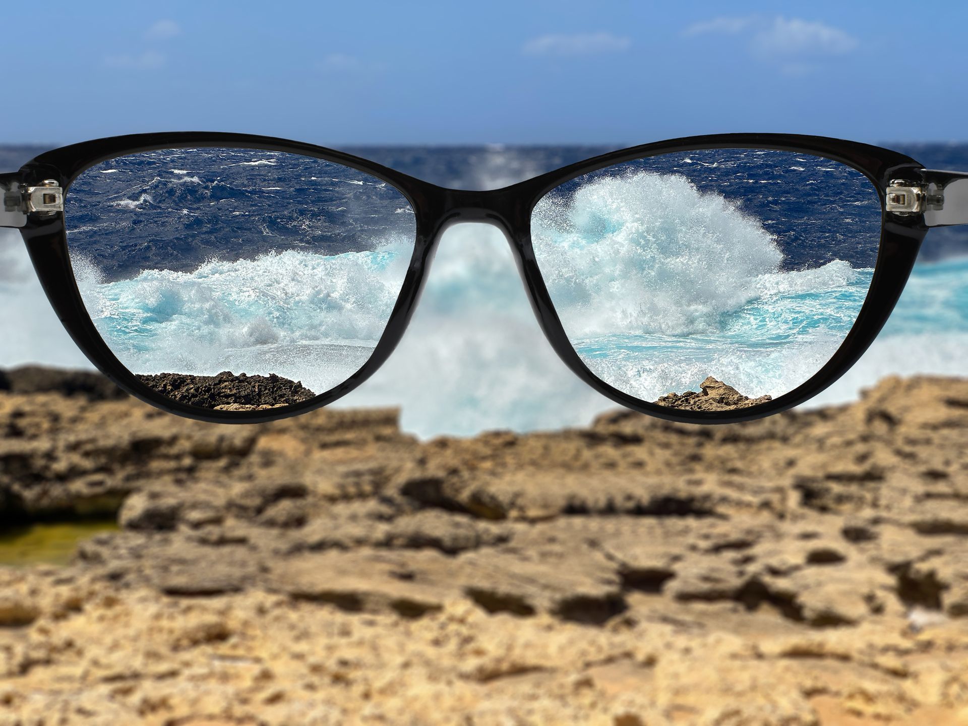 A pair of sunglasses with a picture of the ocean in the lenses.