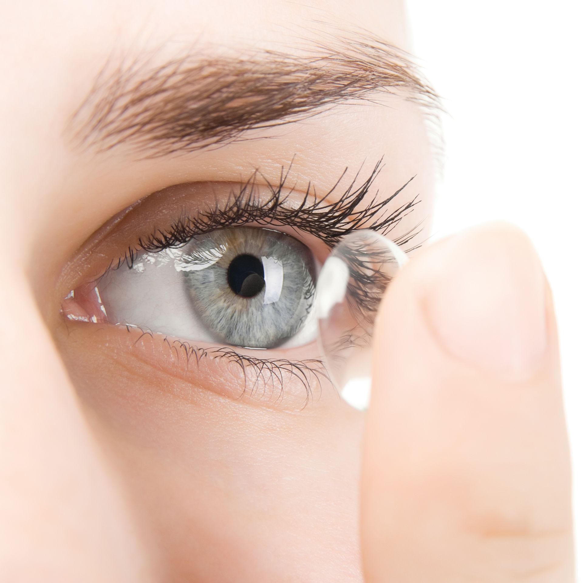 A woman is putting a contact lens in her eye