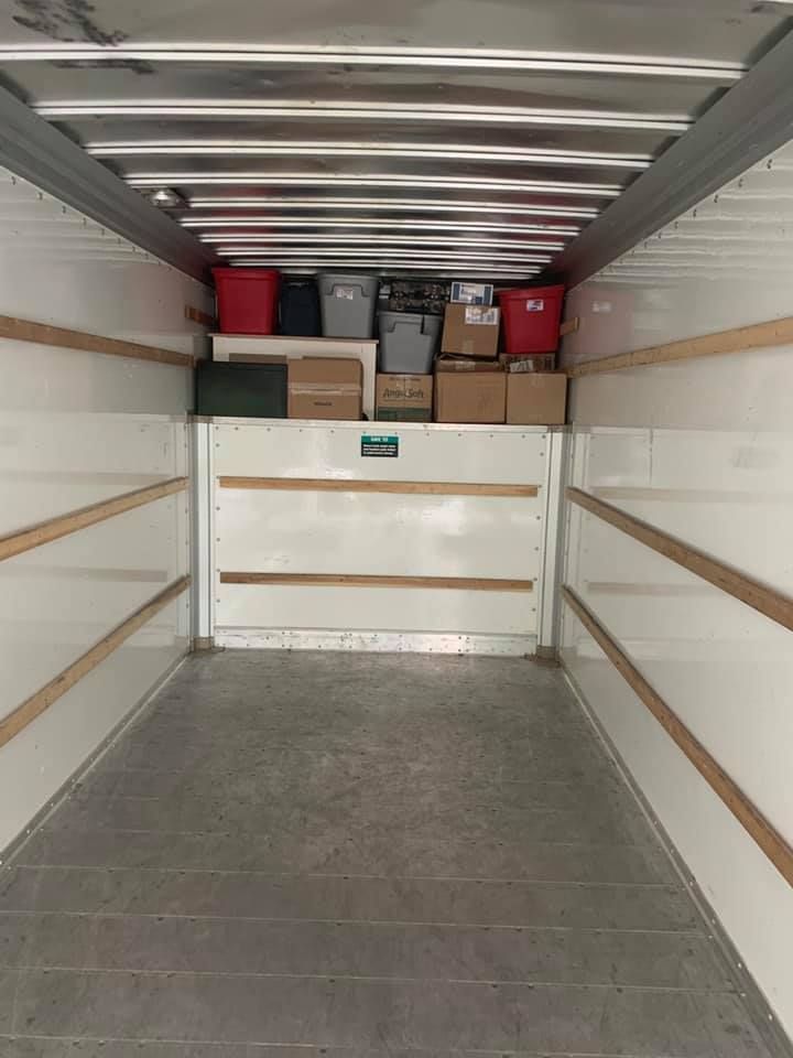 Empty cargo truck bed with boxes and bins on a top shelf.