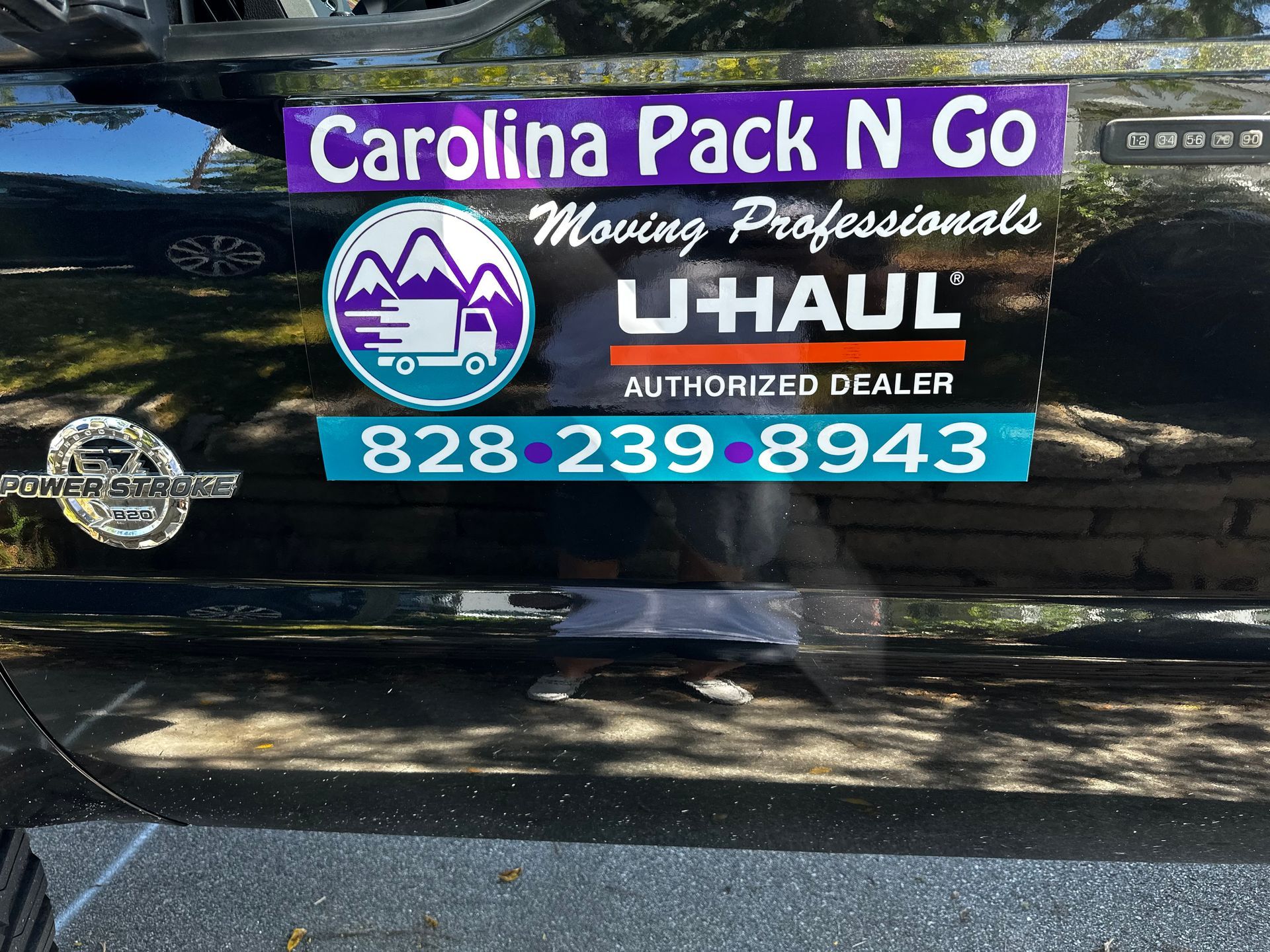 Carolina Pack N Go U-Haul Authorized Dealer sign on black vehicle with blue and purple text.