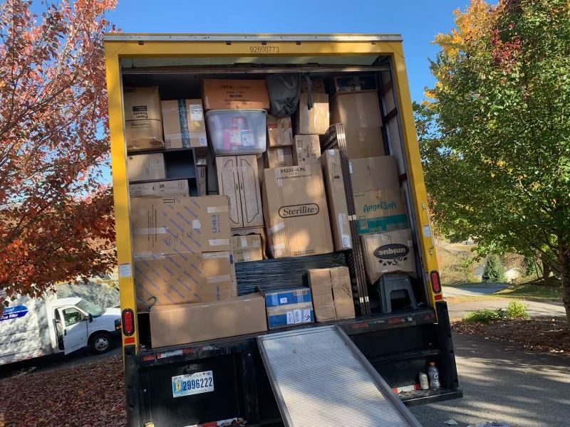 Open back of a yellow truck filled with moving boxes, parked outside with trees in view.