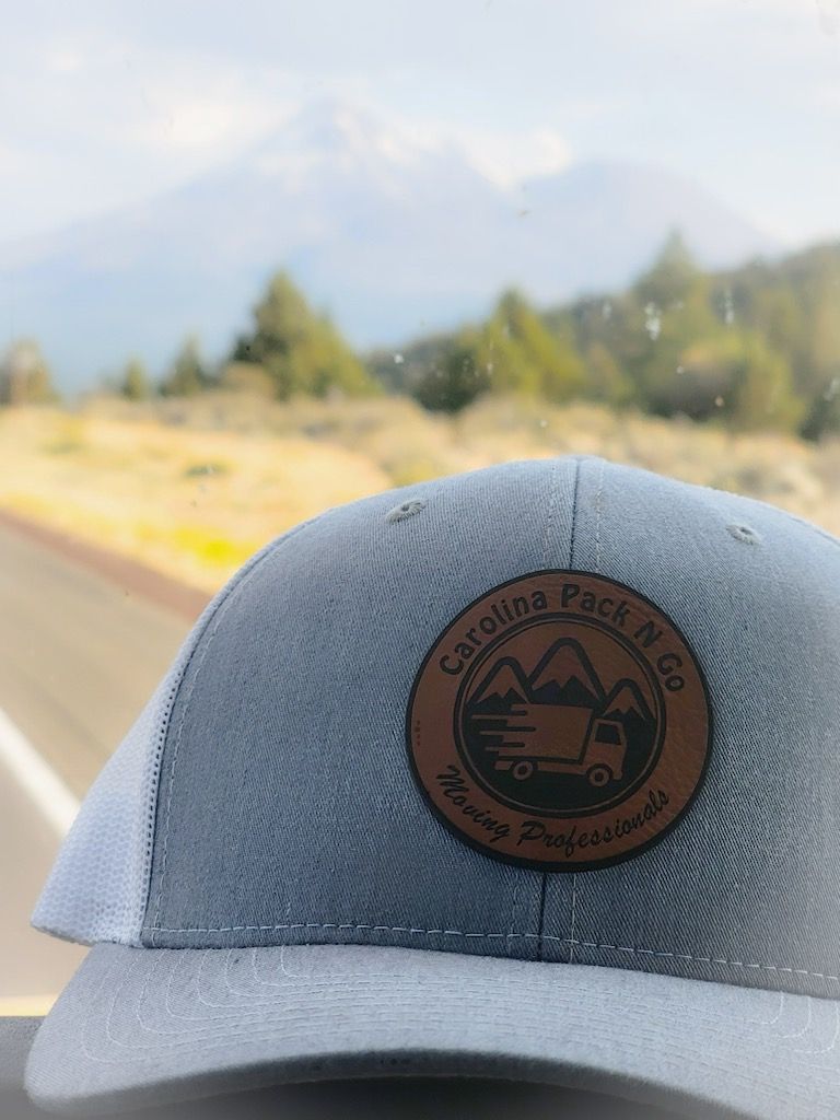 Gray cap with Carolina Pack & Co. logo, mountain backdrop, highway.