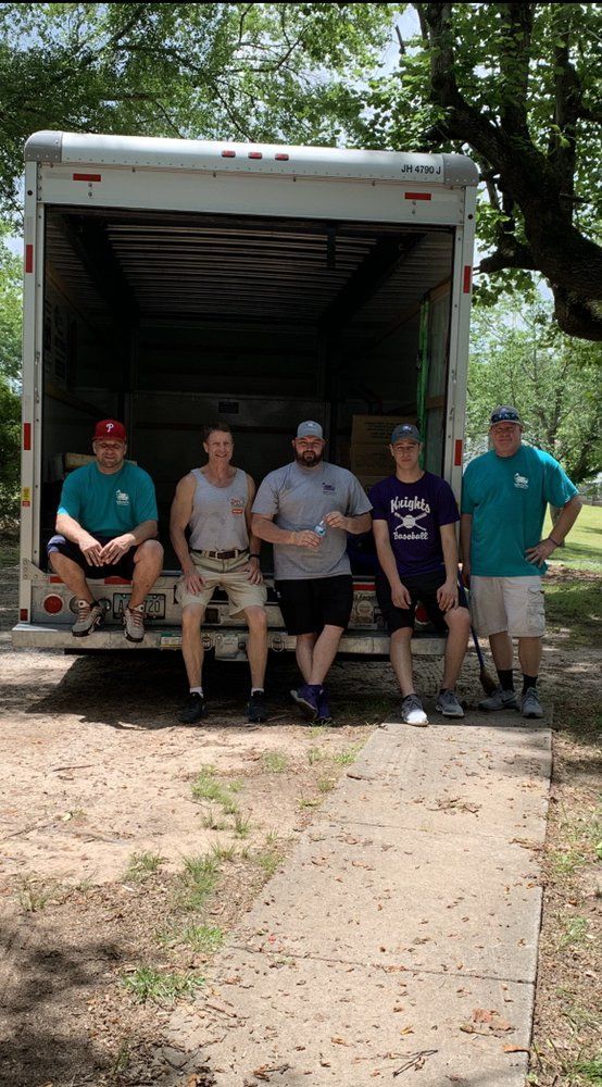 Five men stand in front of a moving truck, ready to load.