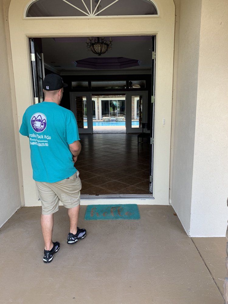 Man in blue shirt walks through an open door into a home, view includes a pool in the backyard.