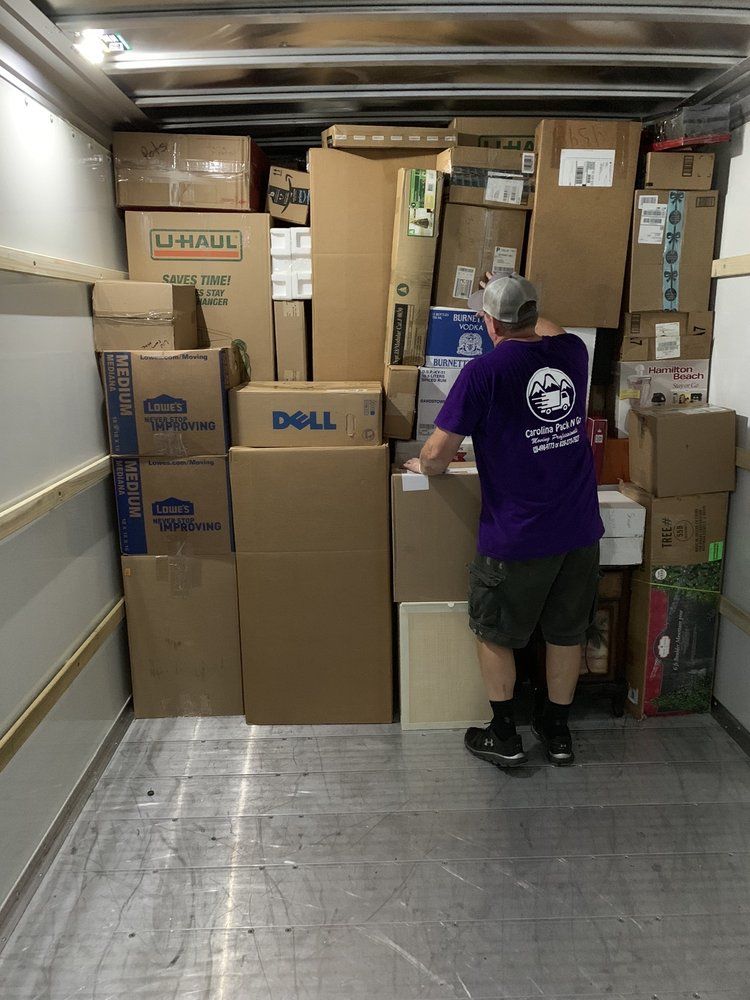 Man loading boxes into a moving truck.  Boxes of various sizes and brands are stacked high, covering most of the space.