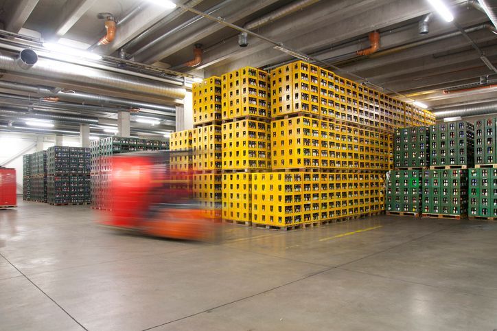 Un carrello elevatore sta attraversando un magazzino pieno di casse.