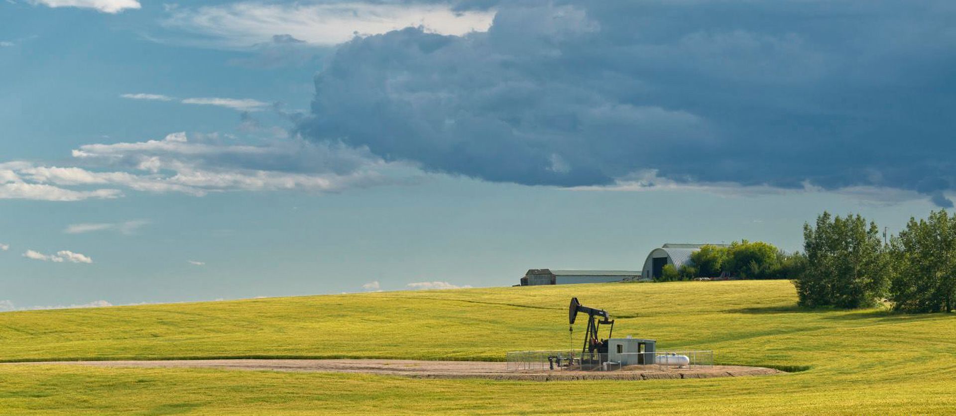 Oil pump in a field under a cloudy sky.