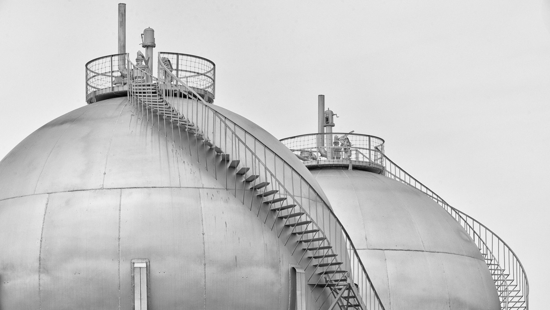 Two large, round industrial storage tanks with external staircases and top platforms.