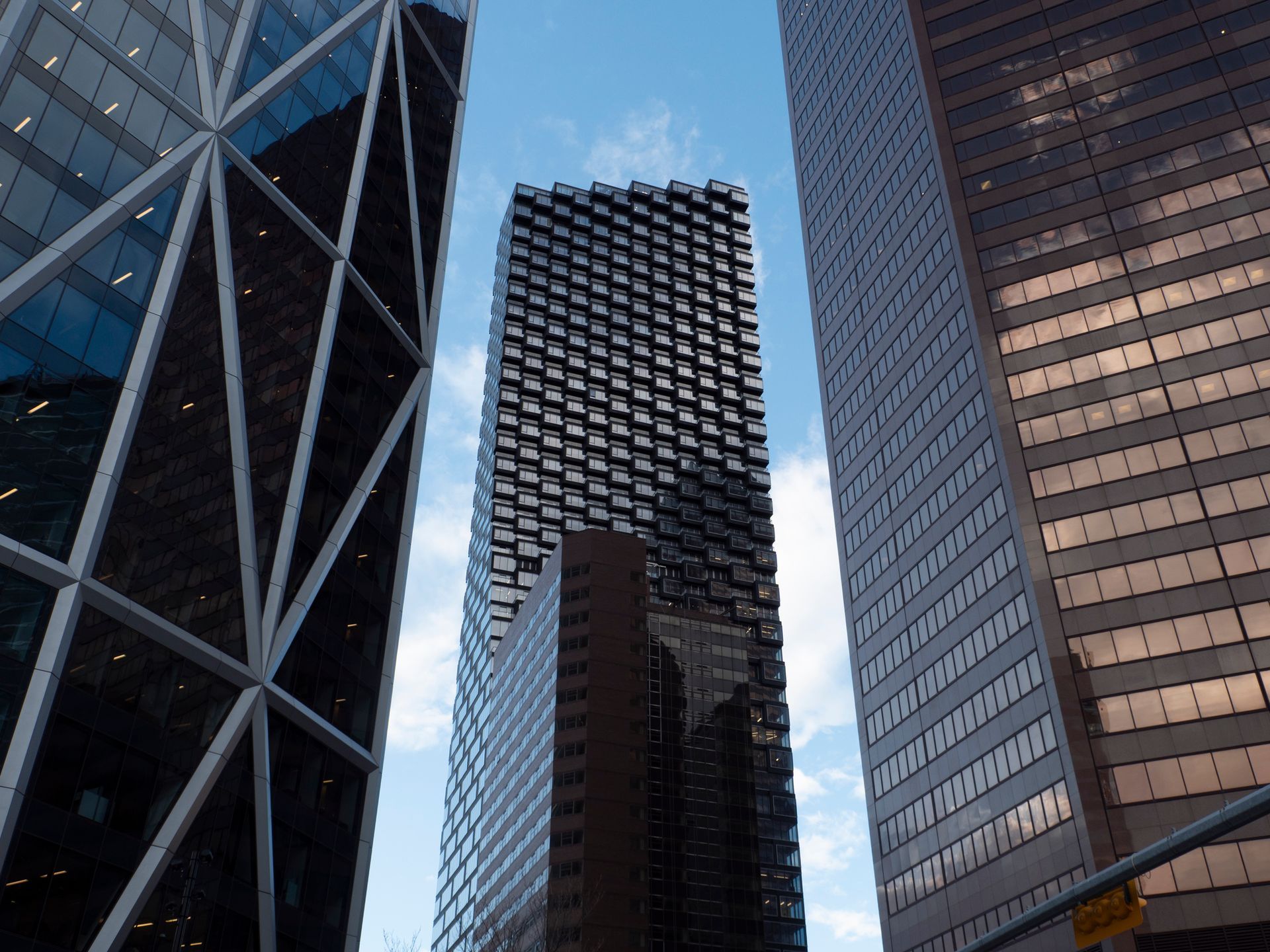 Skyscrapers against a blue sky, framing a textured, dark central building.