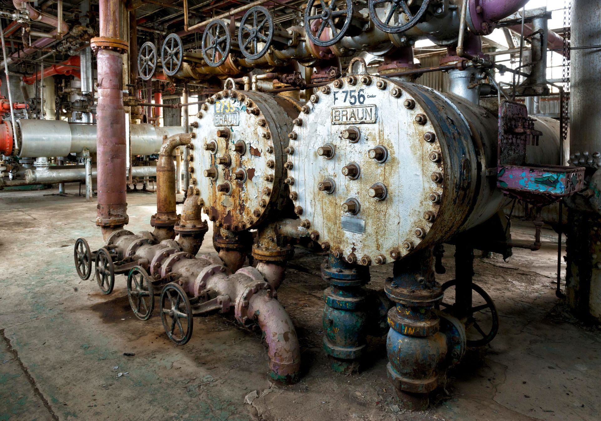 Rusty industrial pipes and valves in a factory setting.
