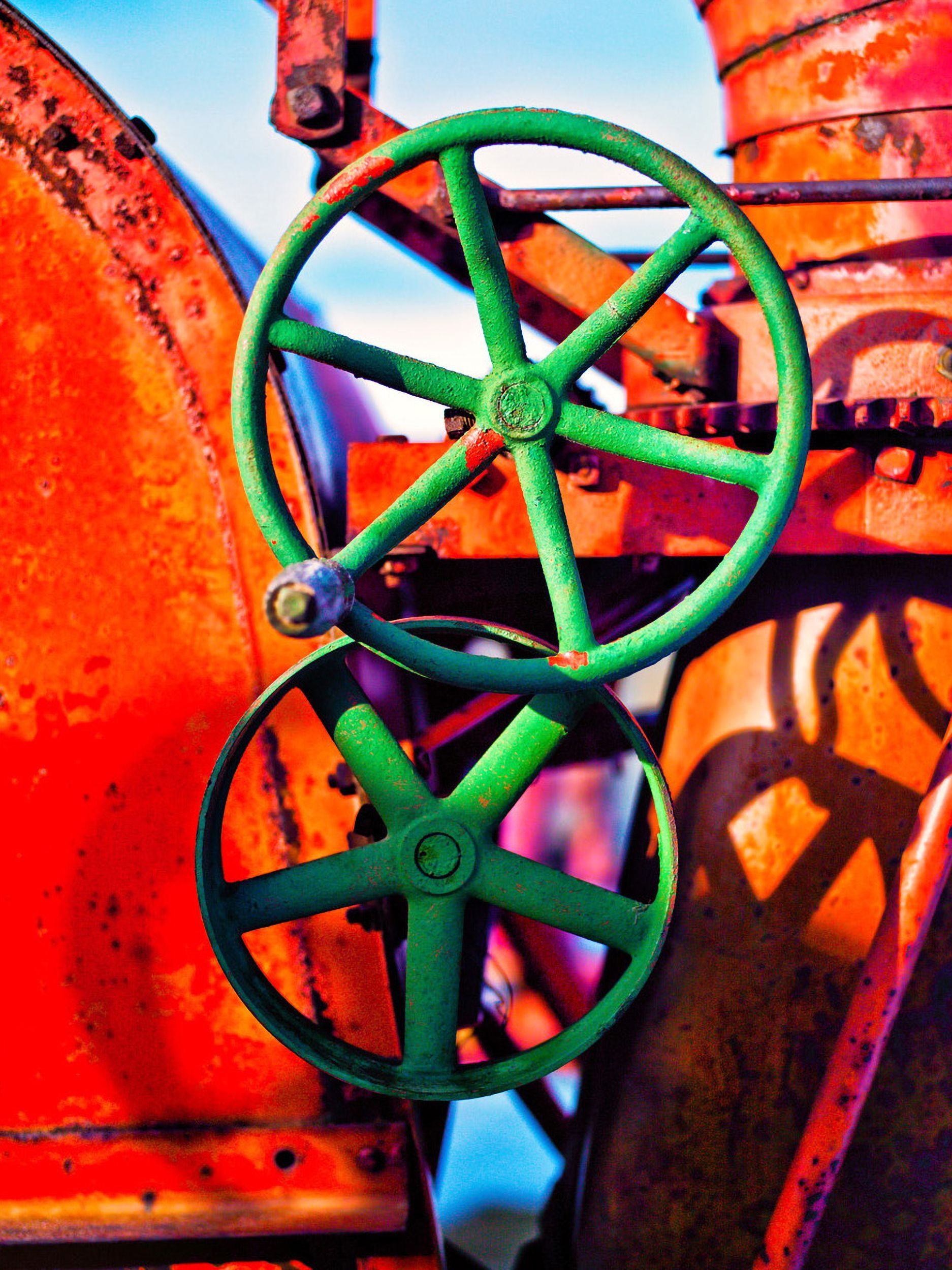 Two green industrial valves on a rusty red and orange machine.