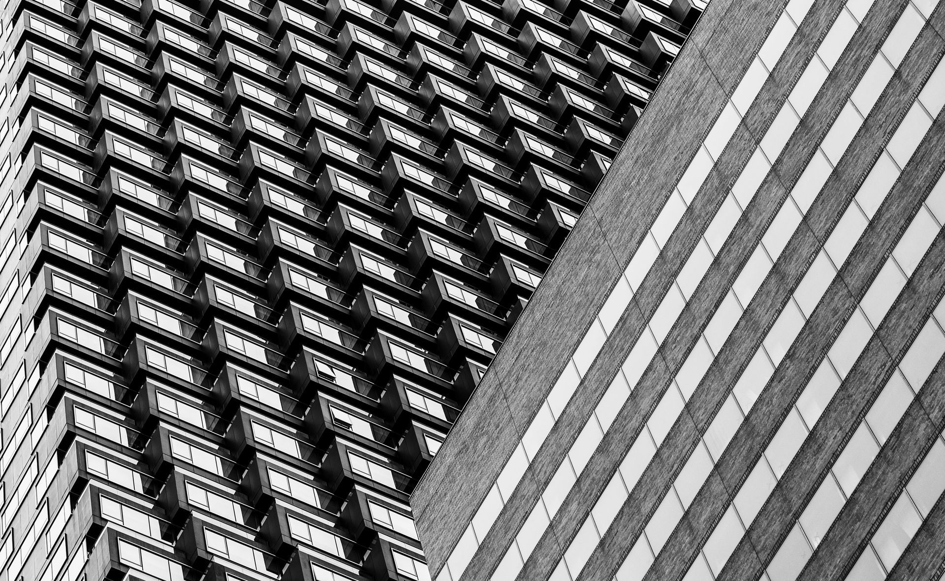 Black and white photograph of two skyscrapers. One with many windows, the other with vertical stripes.