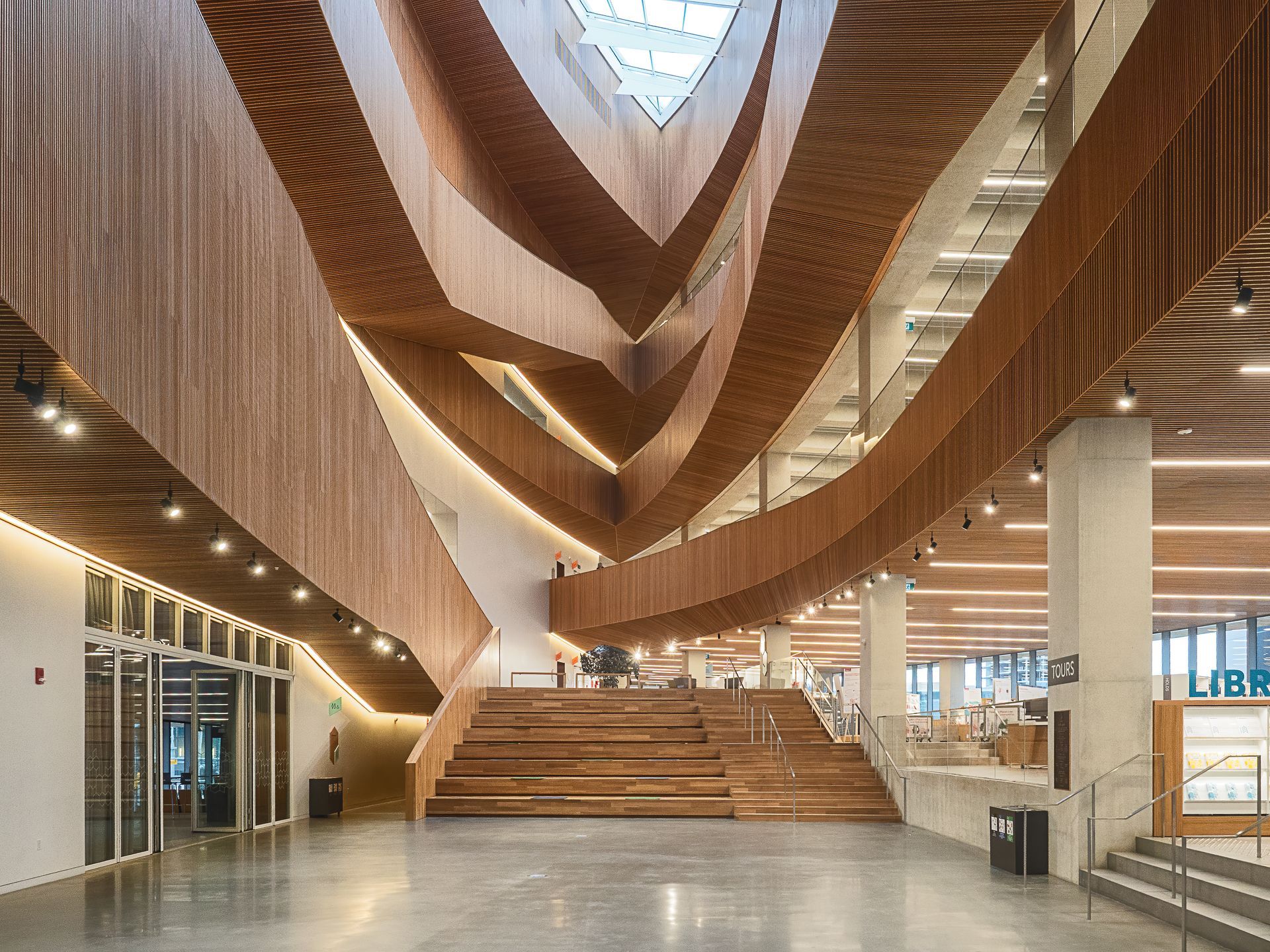 Interior view of a modern library with wooden architectural elements and large central staircase.