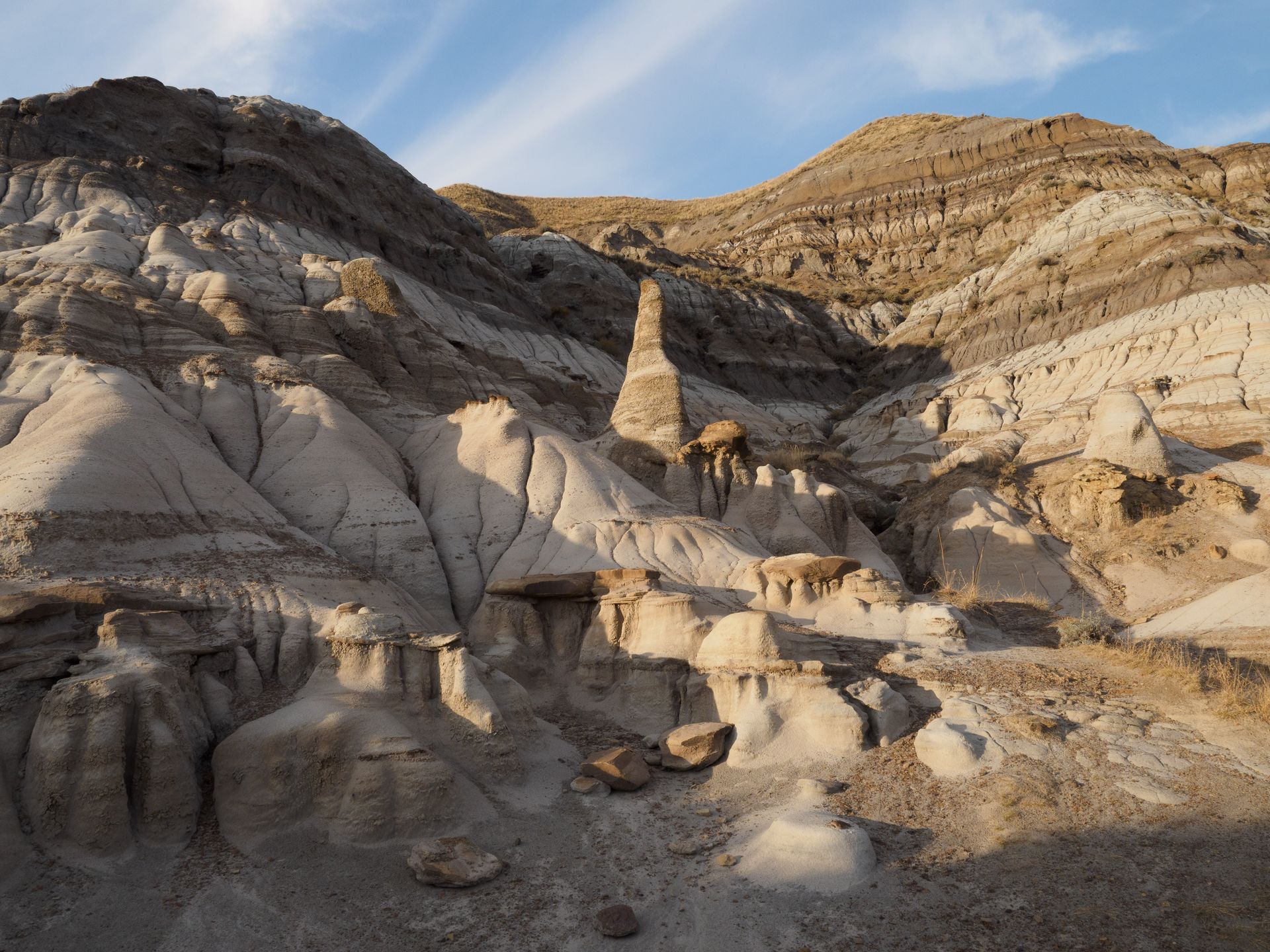 Eroded rock formations in desert landscape, with layered sediment and hoodoos.