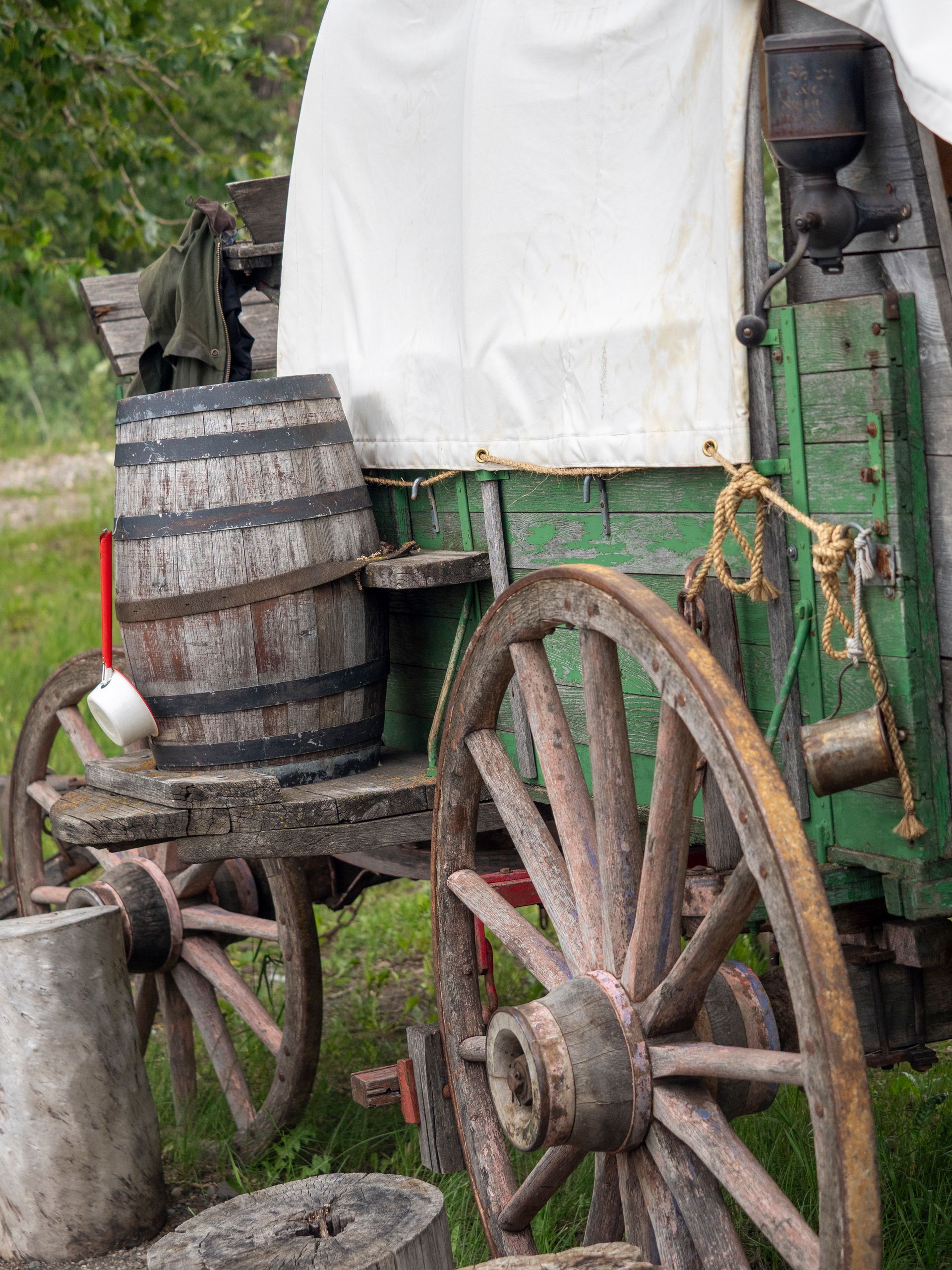 Old wooden wagon with barrel and white canvas cover.