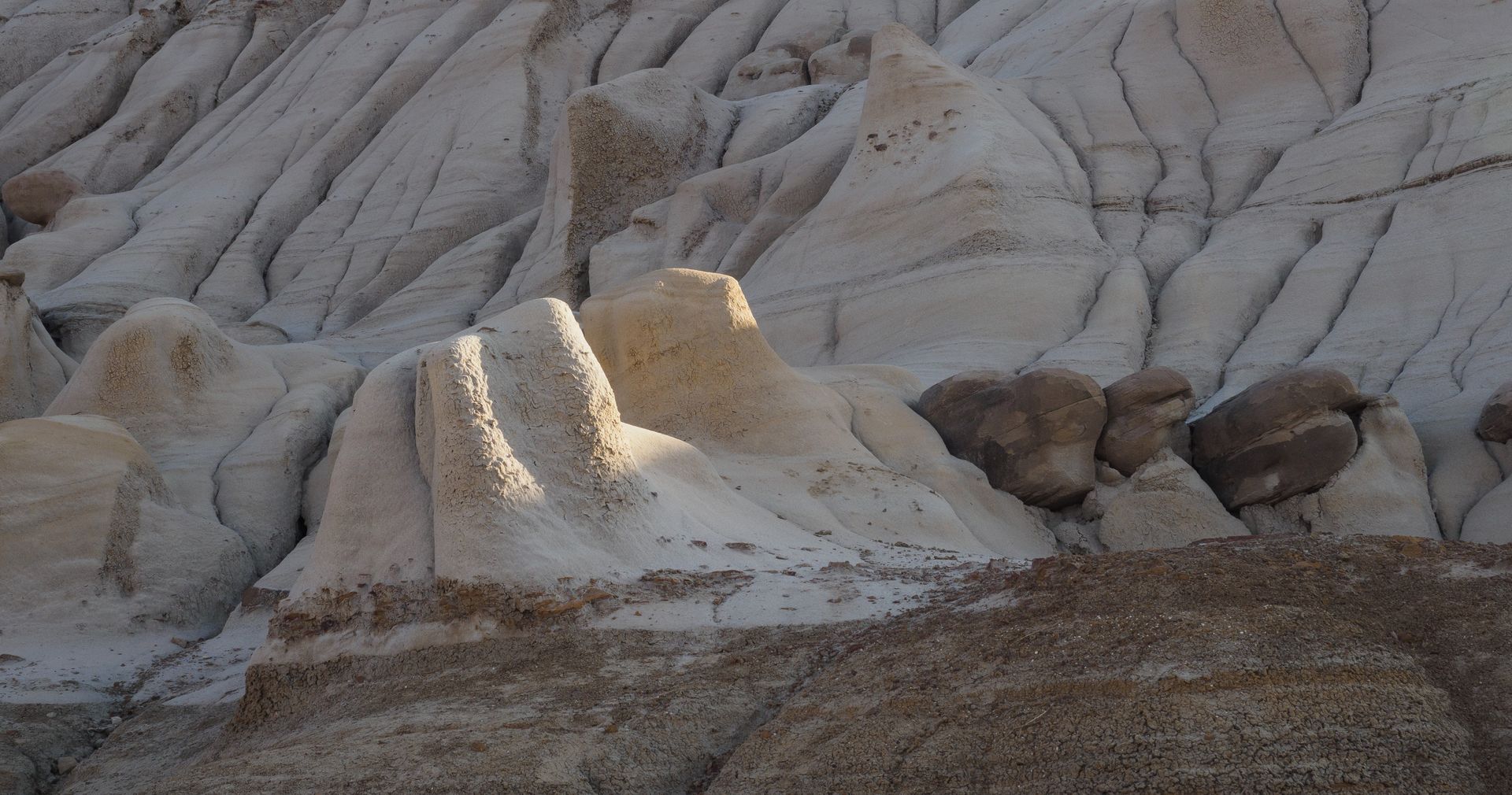 Eroded desert landscape with layered tan and brown rock formations.