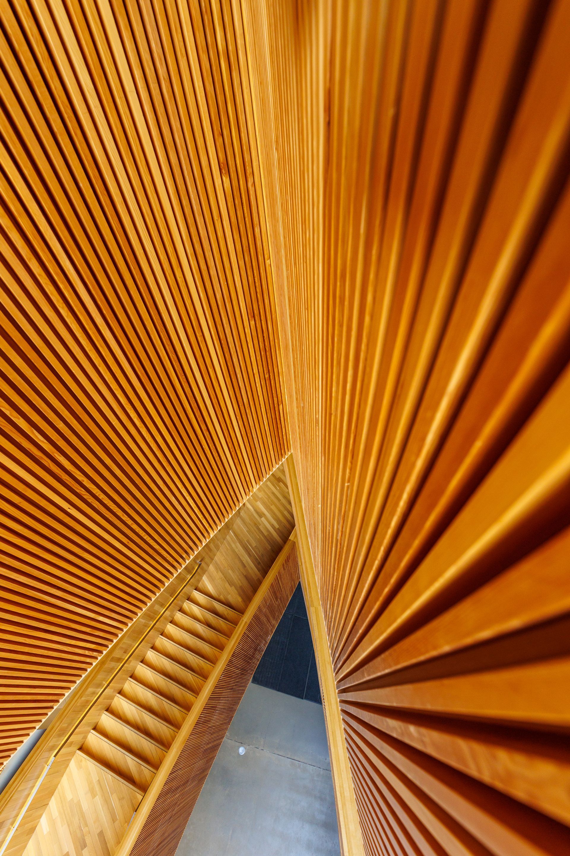 Wooden slatted interior walls meet at angles, creating a triangular space; warm brown tones.