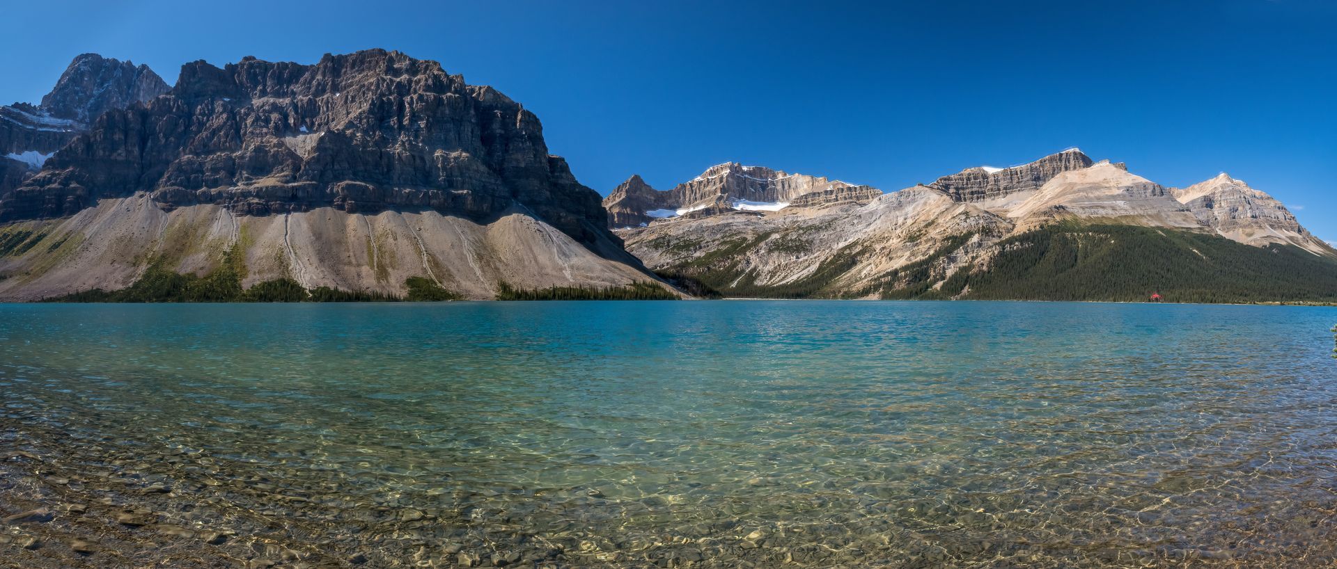Turquoise lake with mountains in the background under a blue sky.