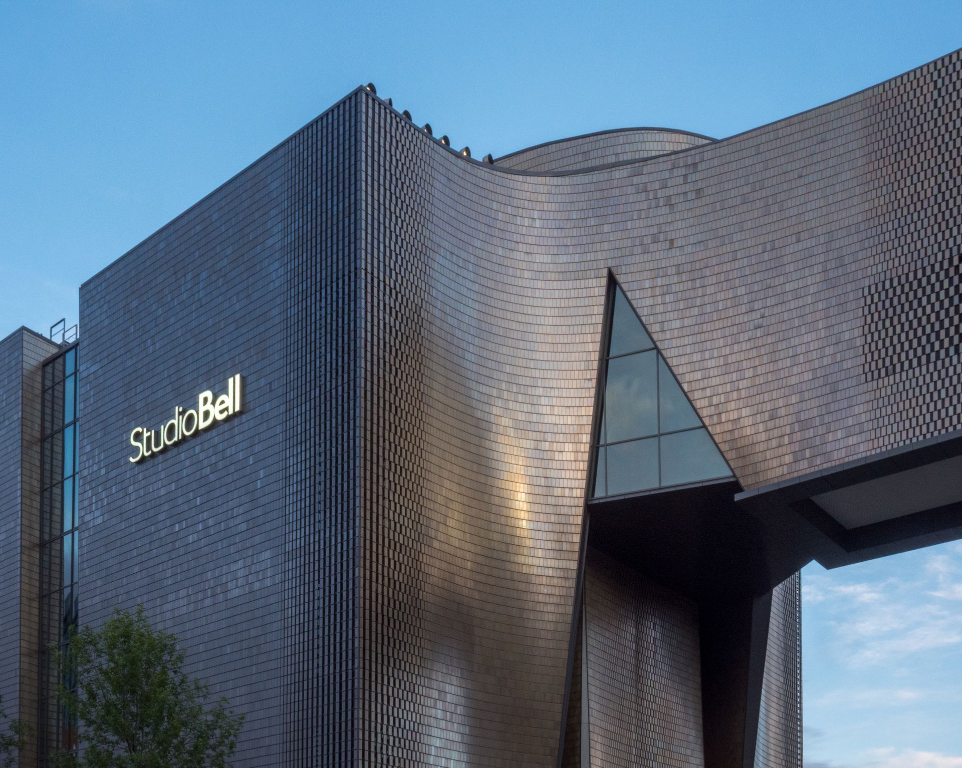 Studio Bell building with a curved, metallic exterior under a blue sky.