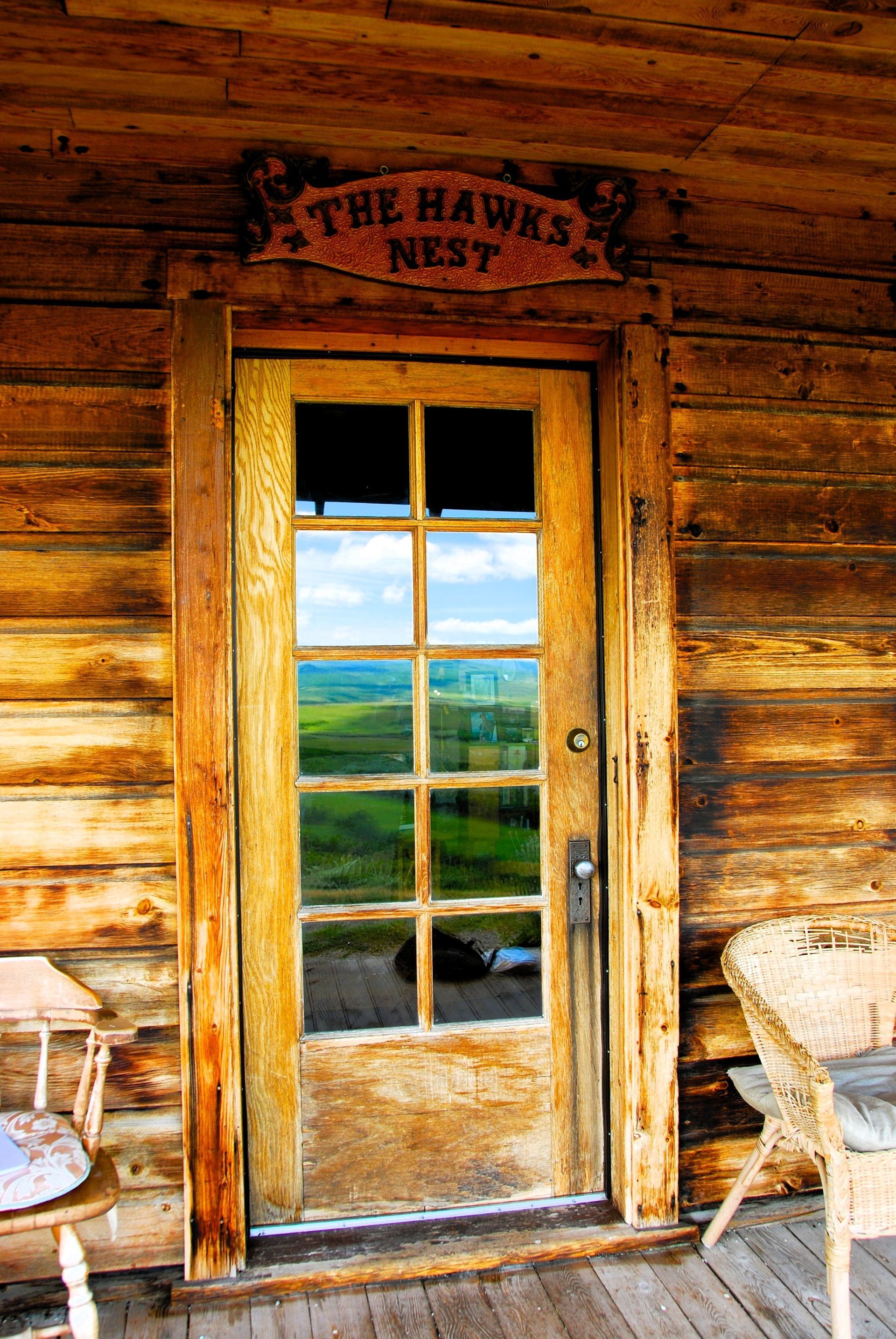 Wooden door with glass panes reflecting a green landscape, 