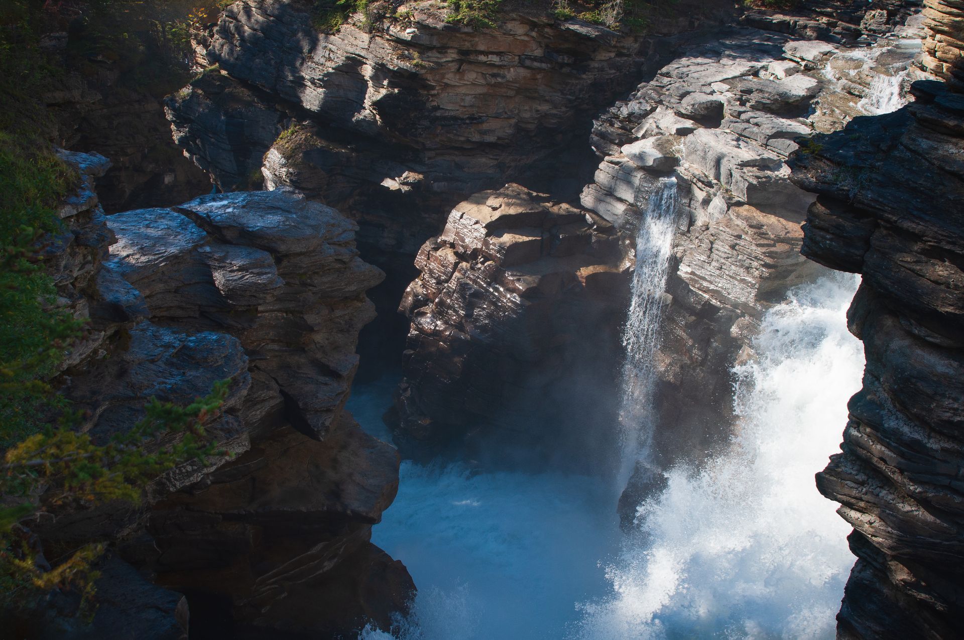 Waterfall cascading through a rocky canyon; white water against dark rock.