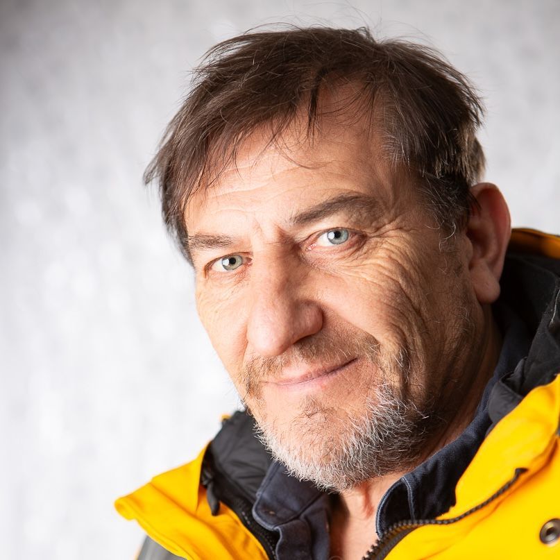 Man with glasses, bald head, and plaid shirt smiling.